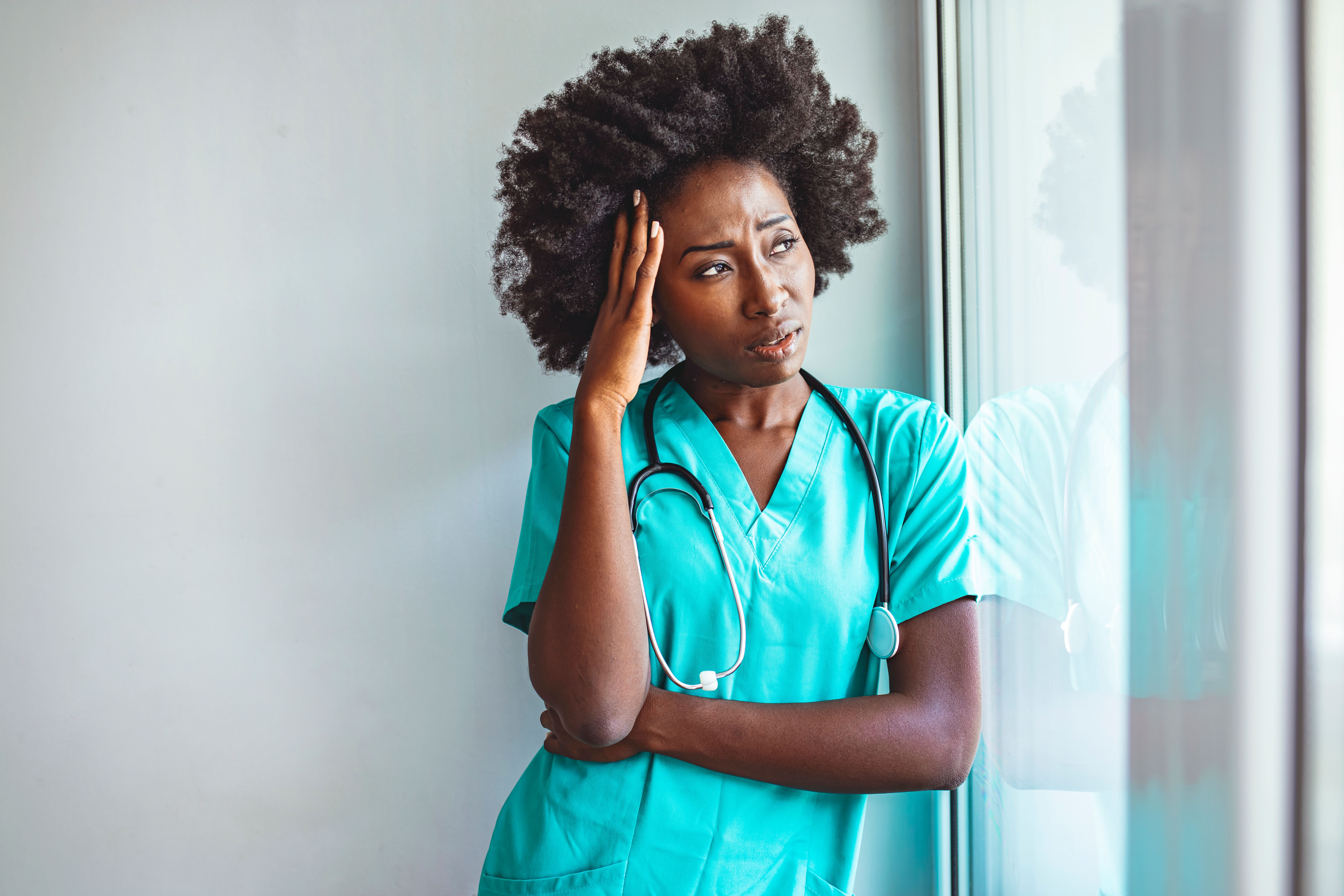 Tired female nurse in hospital corridor.