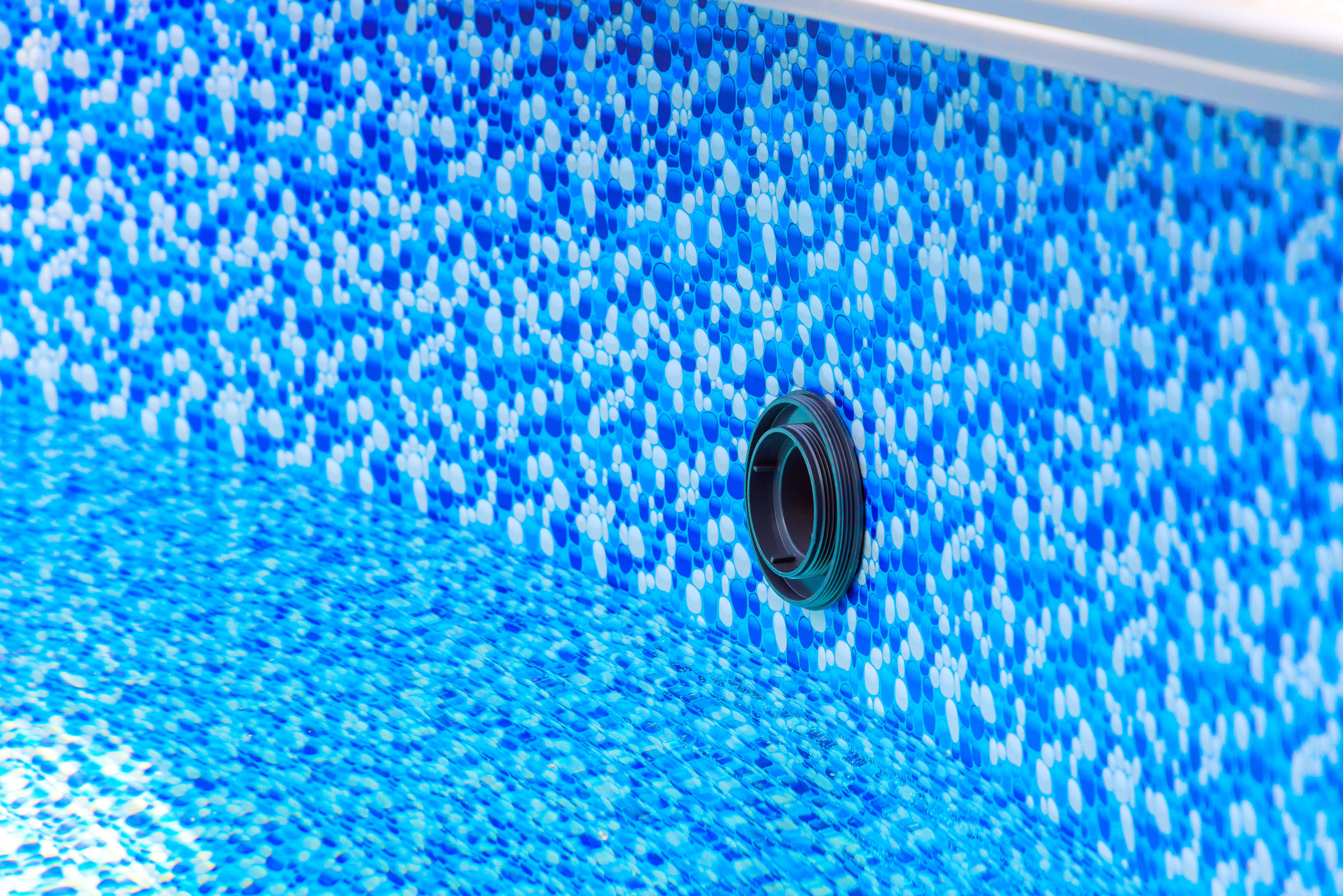Close up view of blue mosaic pool liner with drainage opening visible during