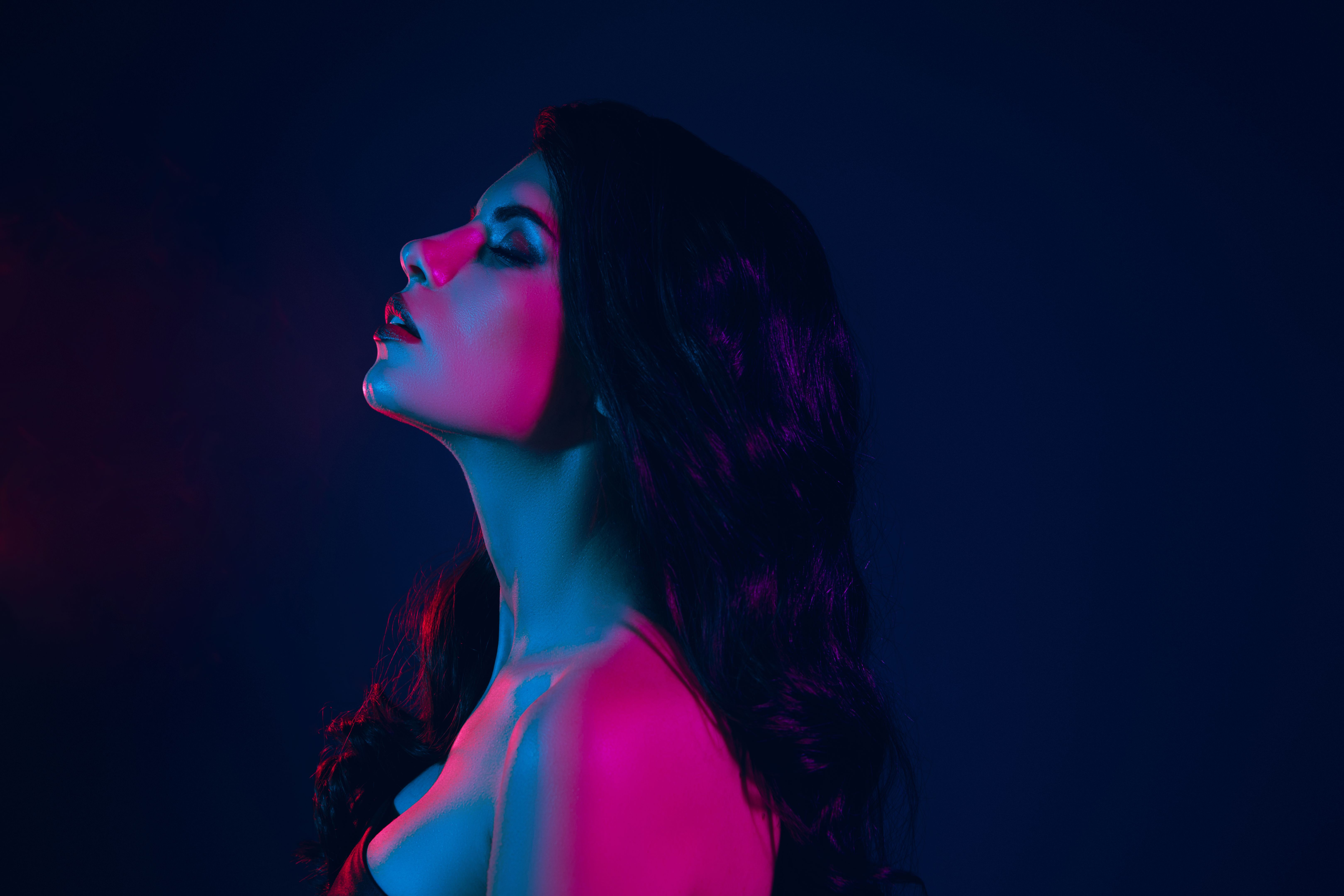 Passionate young woman in neon lighting creating a captivating and stylish atmosphere highlighting beauty