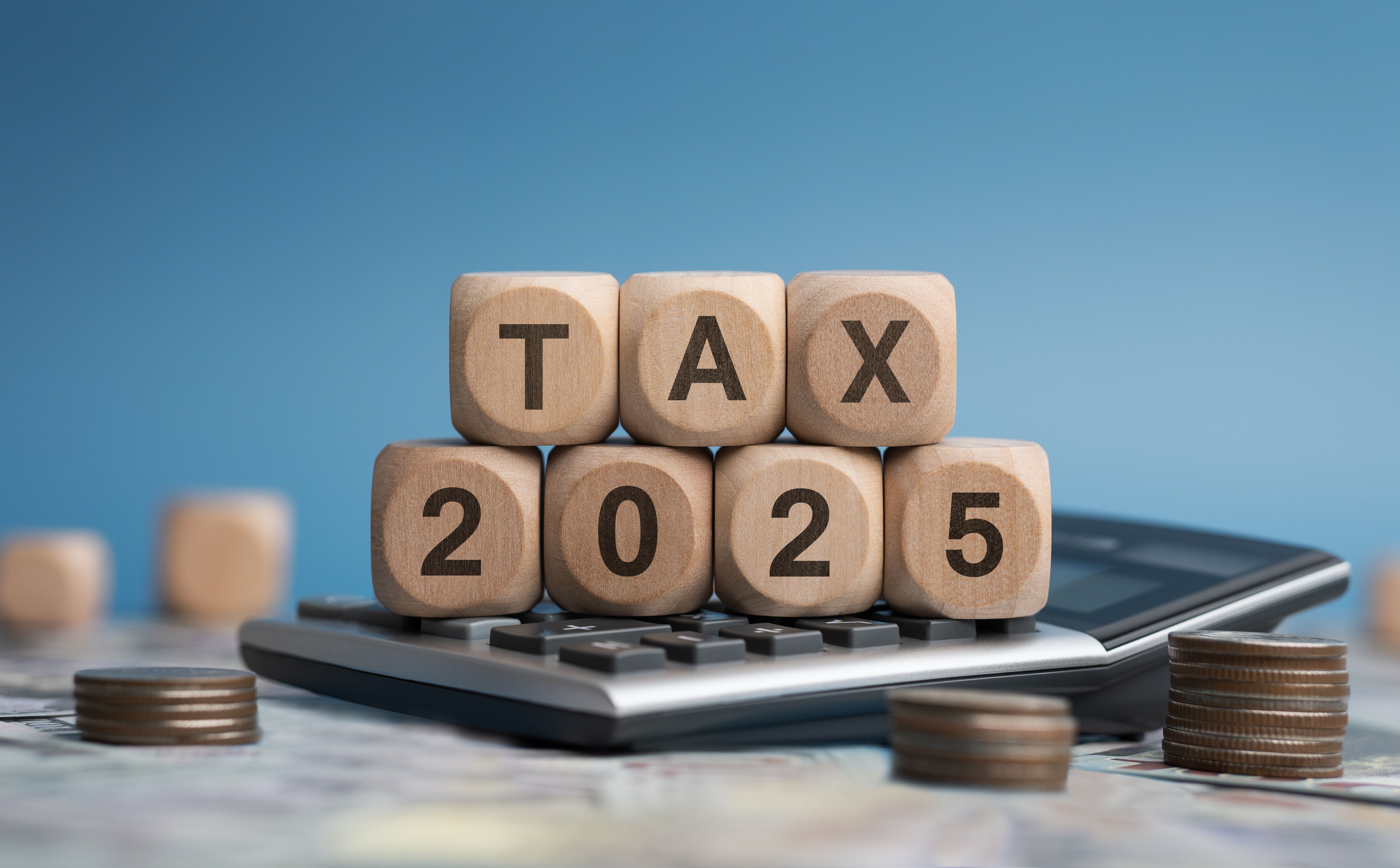 Tax 2025 on wooden blocks. Business and tax concept. Calculator, currency and financial calculations.