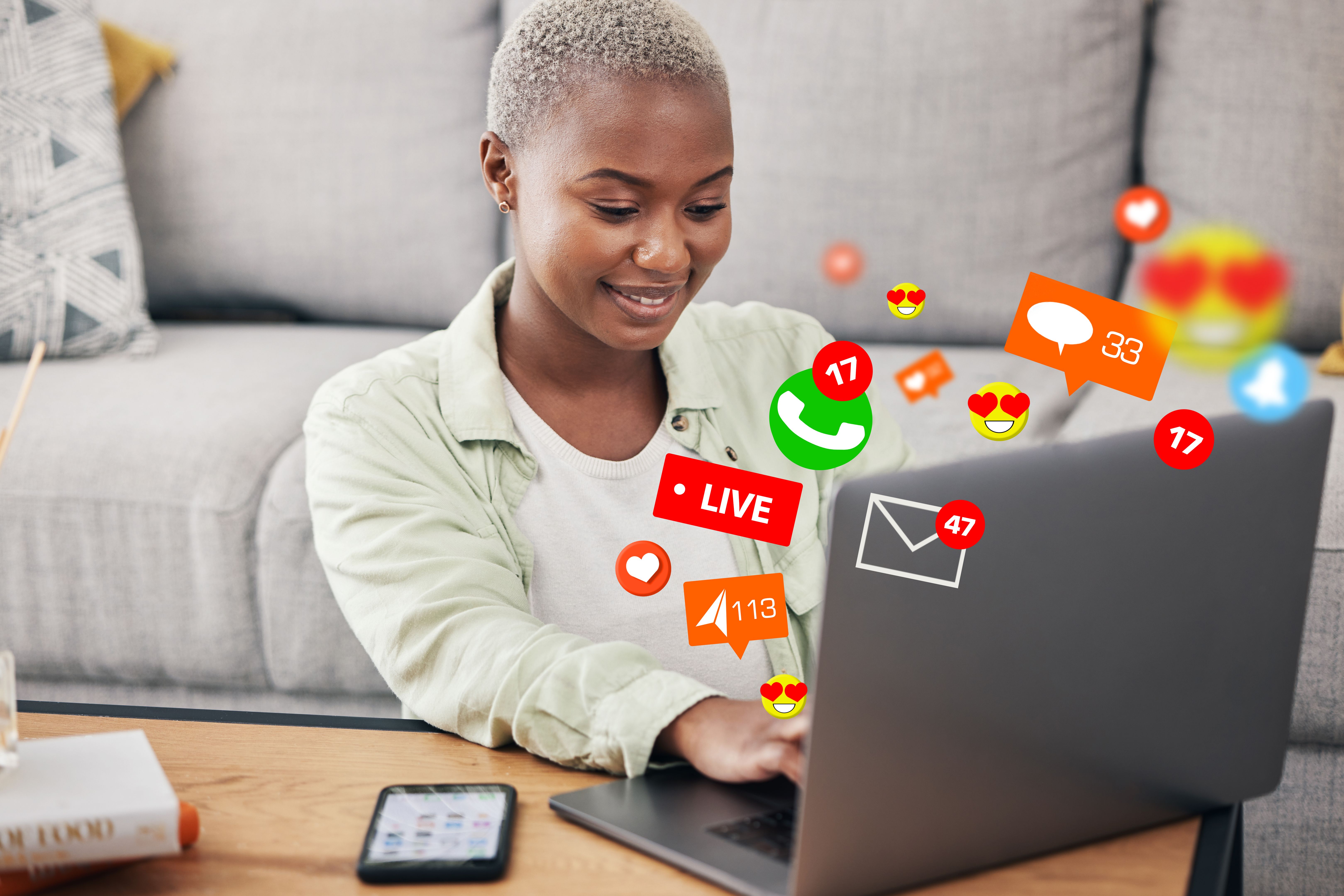 Woman, laptop and social media message icon on home floor for connection, content or platform. African influencer at computer for communication, live streaming and like or love emoji reaction overlay
