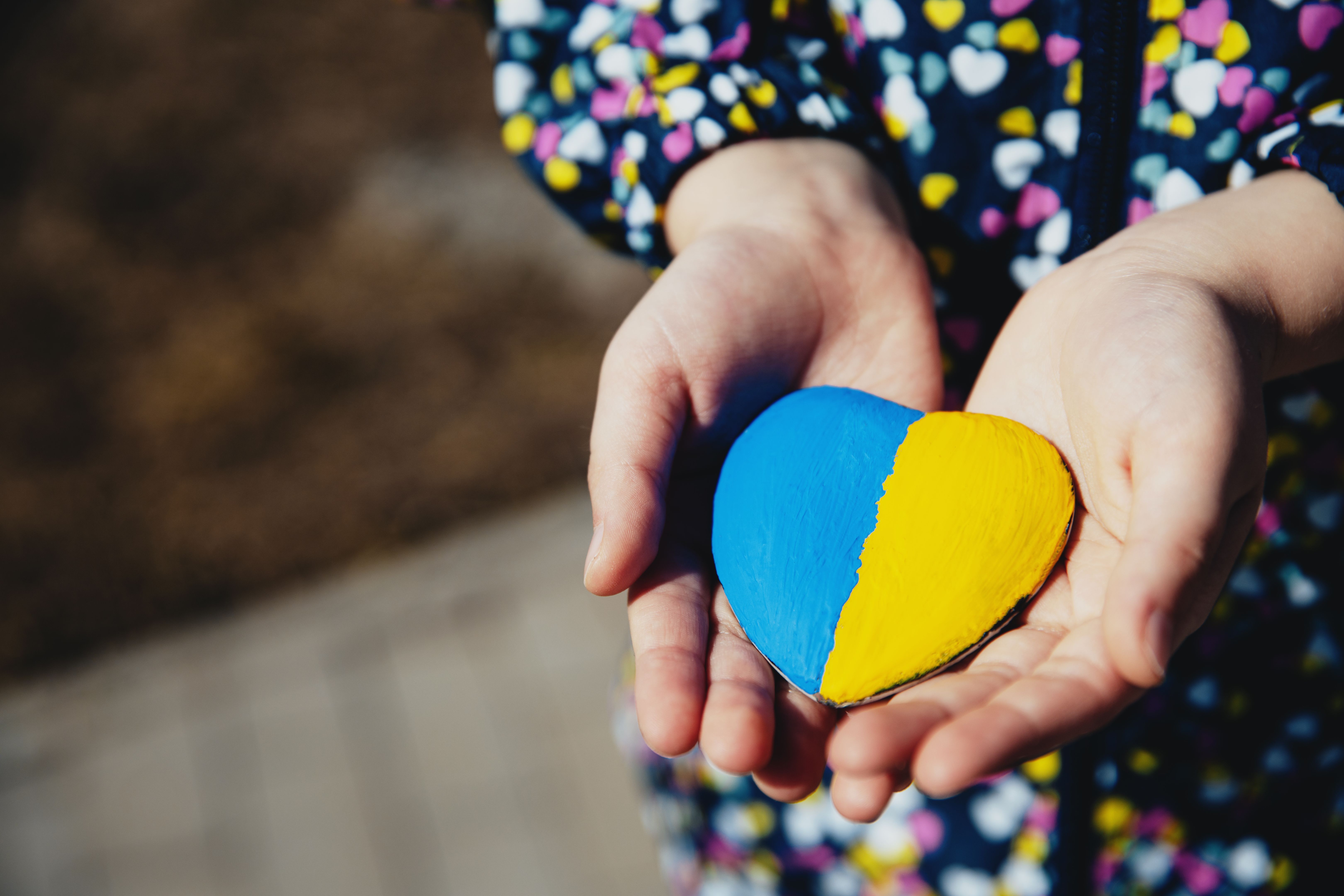 Small little kid hold heart shaped stone with Ukraine national flag or anthem Small little kid hold heart shaped stone with Ukraine national flag or anthem