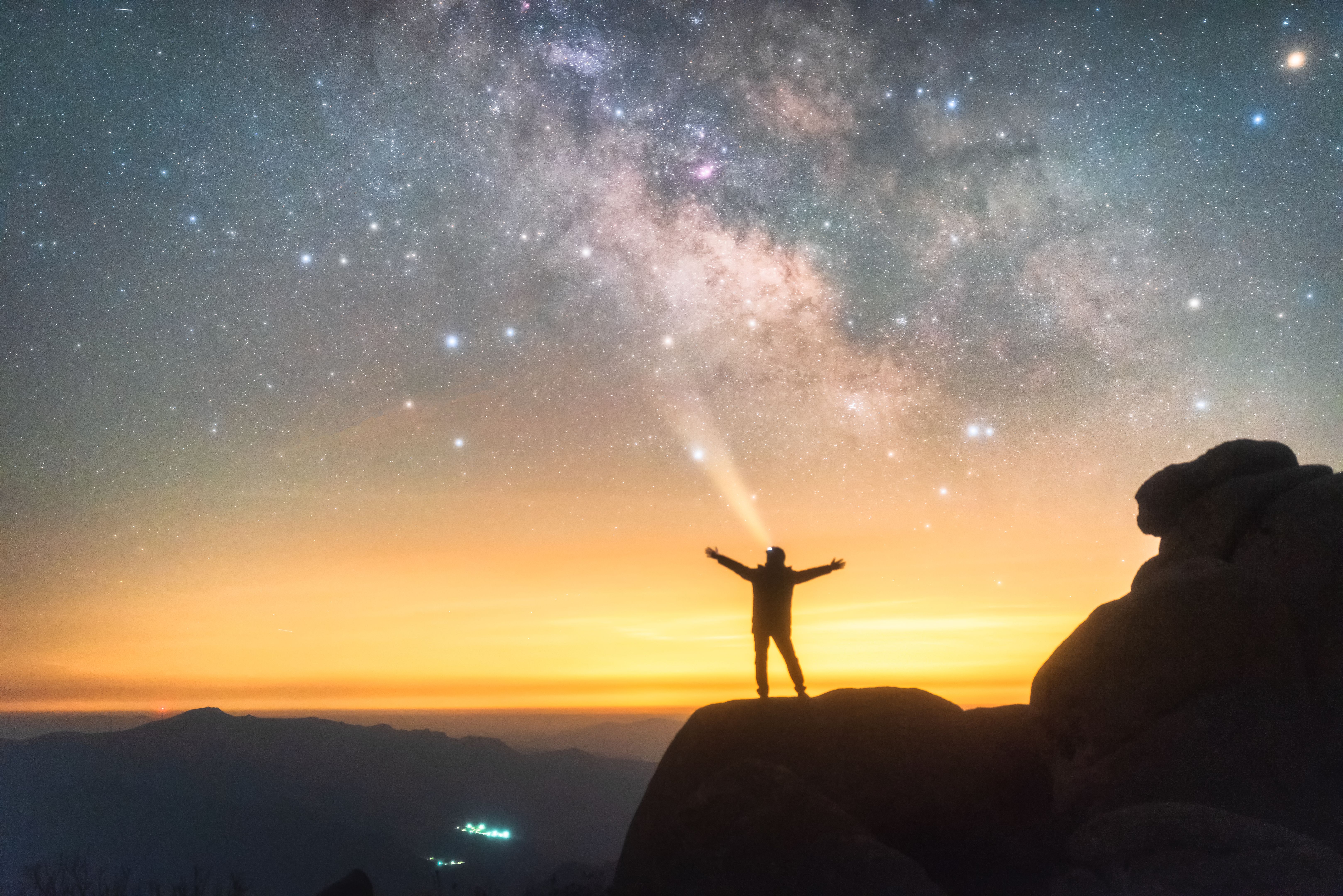 A man standing on the mountaintop admiring the vast Milky Way