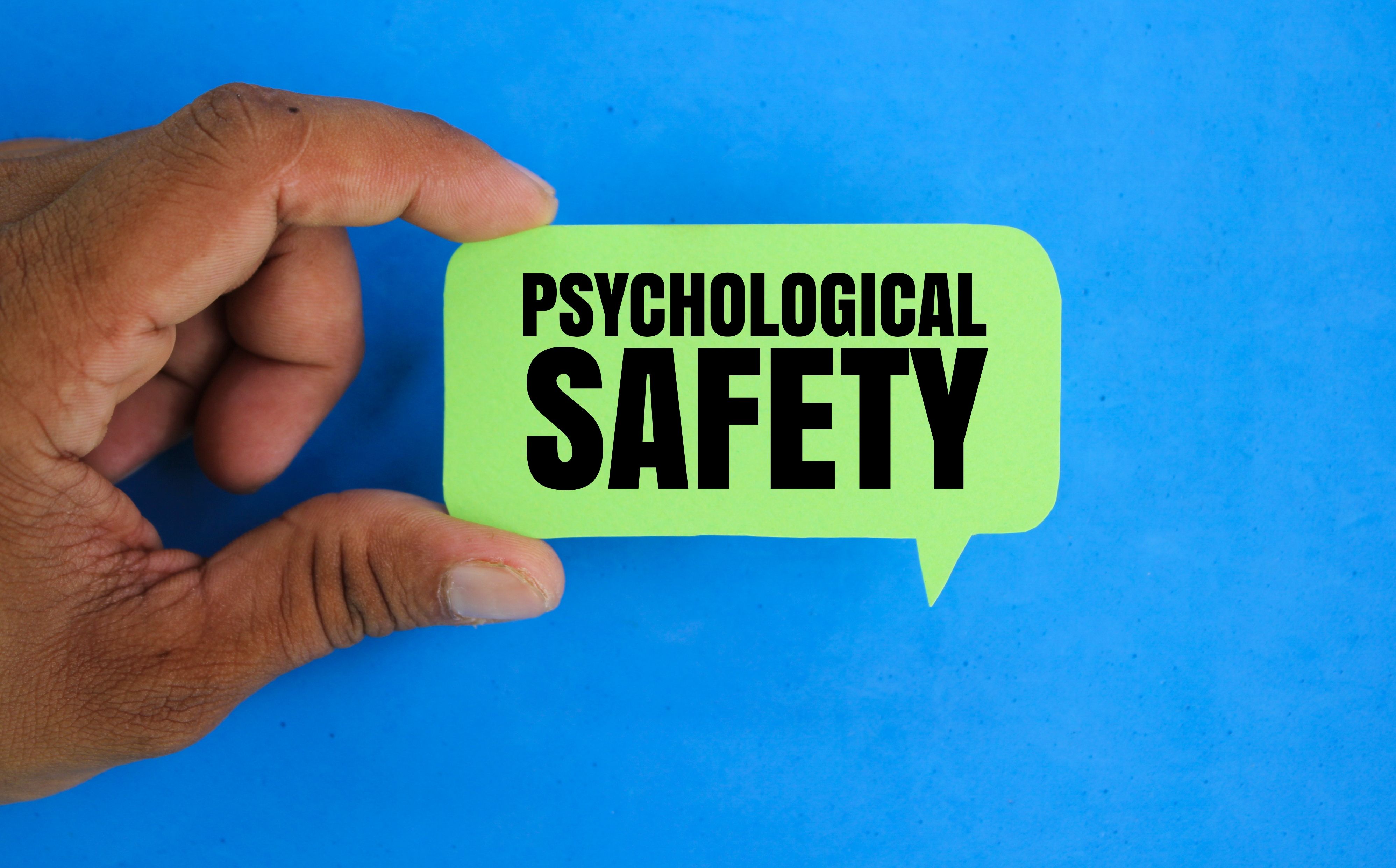 hand holding a conversation bubble with the word Psychological Safety. PSYCHOLOGICAL concept