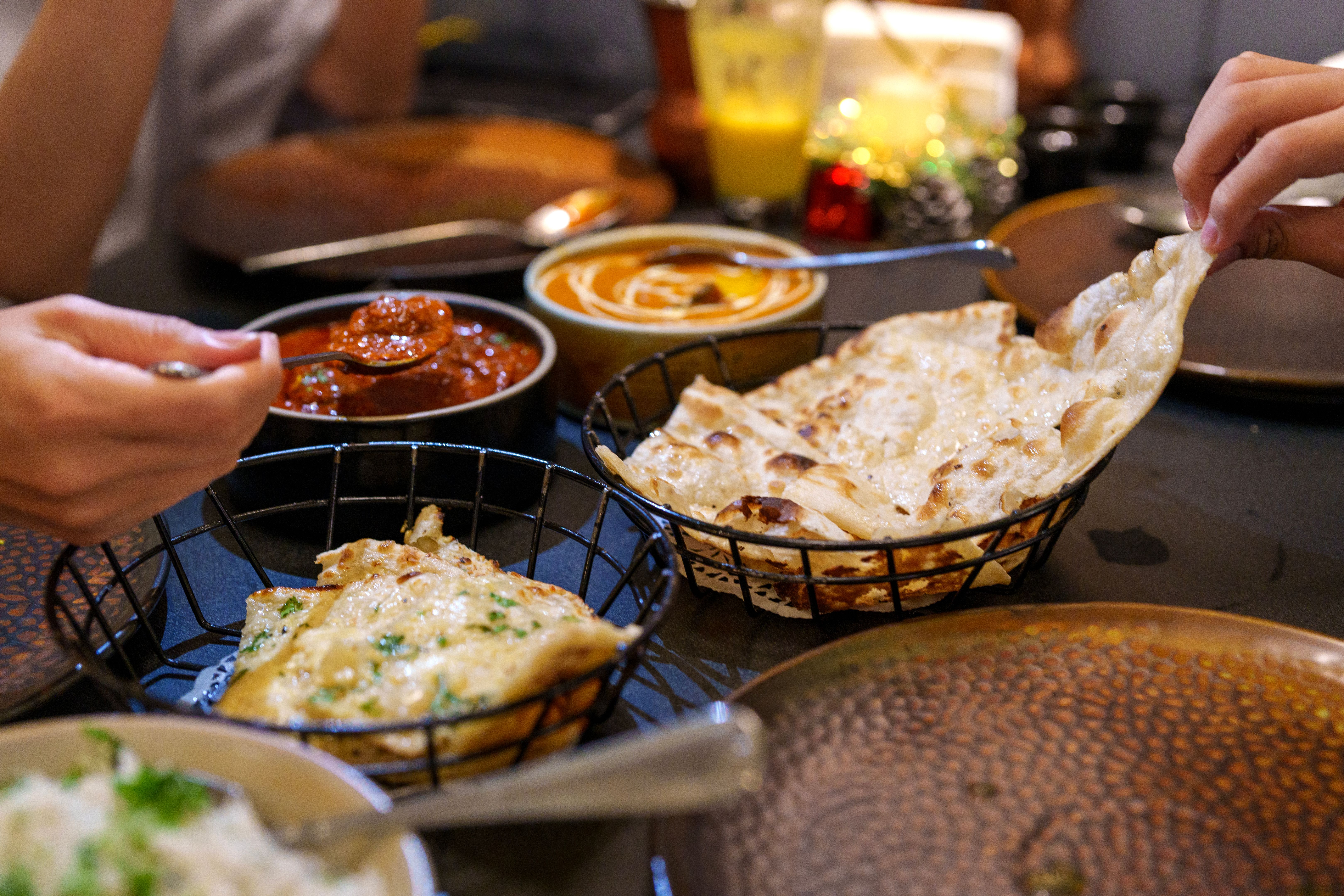 Sharing Garlic Naan with Butter Chicken at a Indian restaurant Sharing Garlic Naan with Butter Chicken at a Indian restaurant