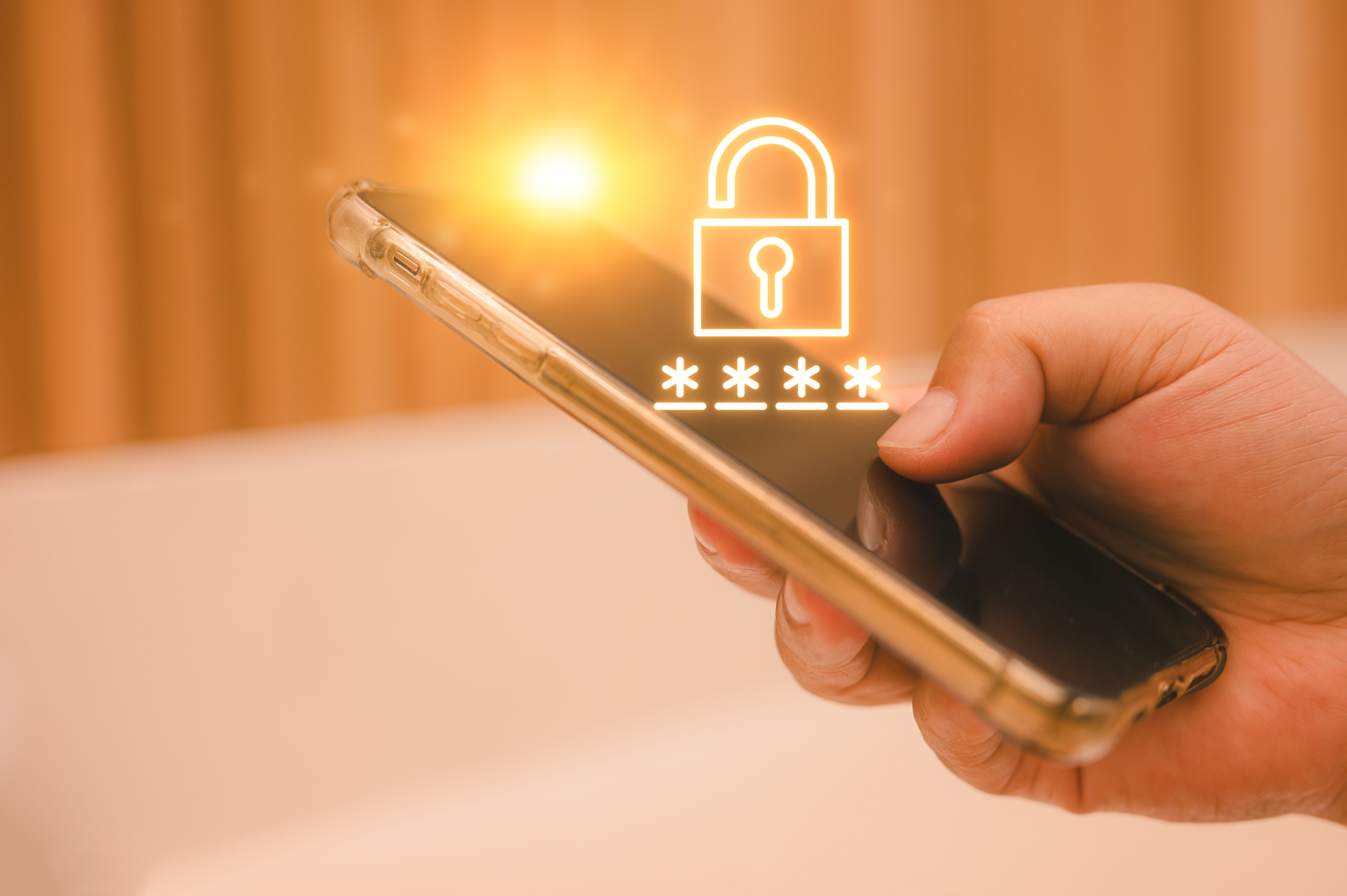 Businessman hand holding smartphone with security key lock icon on the device screen. Privacy protection, internet and mobile security concept Businessman hand holding smartphone with security key lock icon on the device screen. Privacy protection, internet and mobile security concept