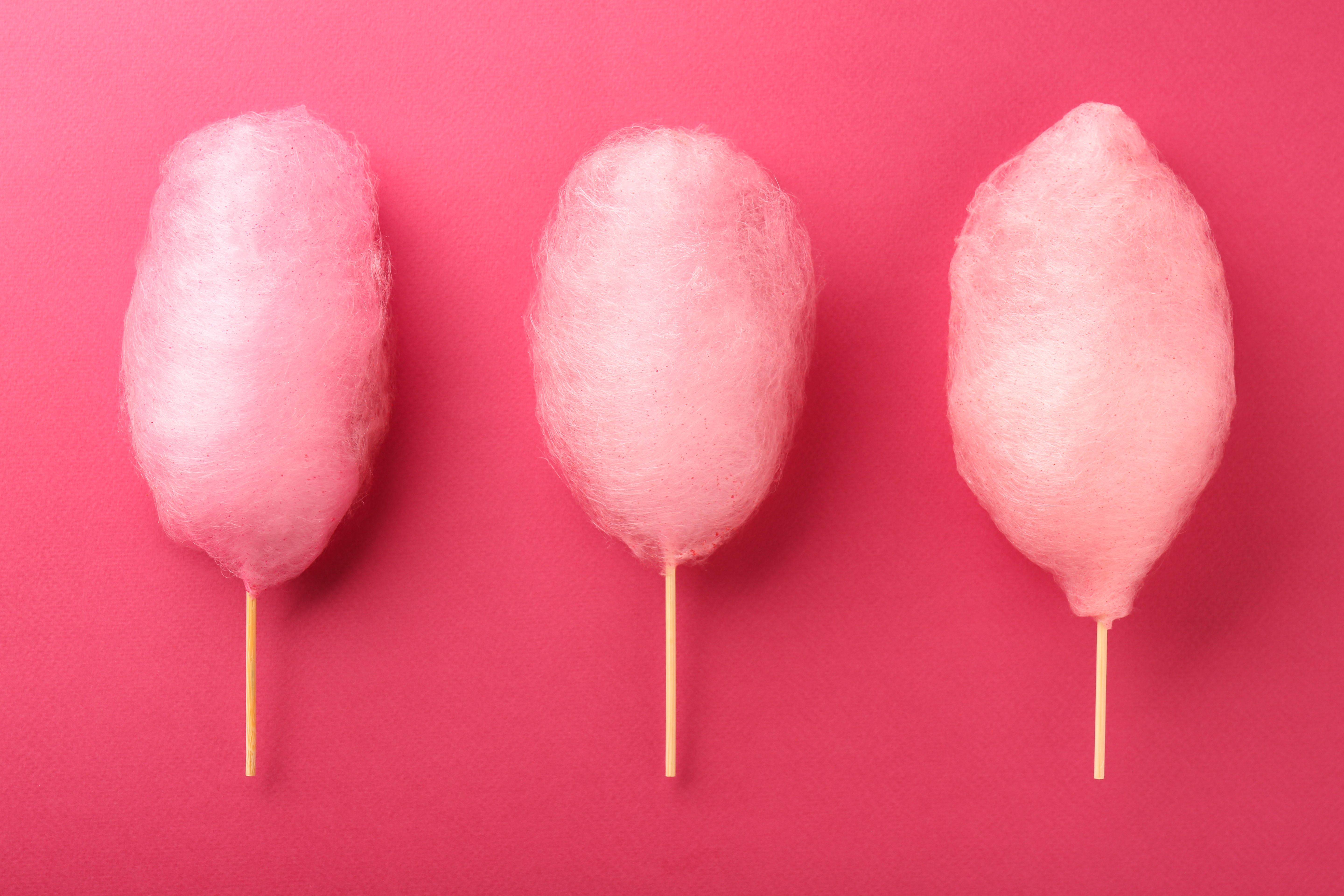 Sweet cotton candies on pink background, flat lay