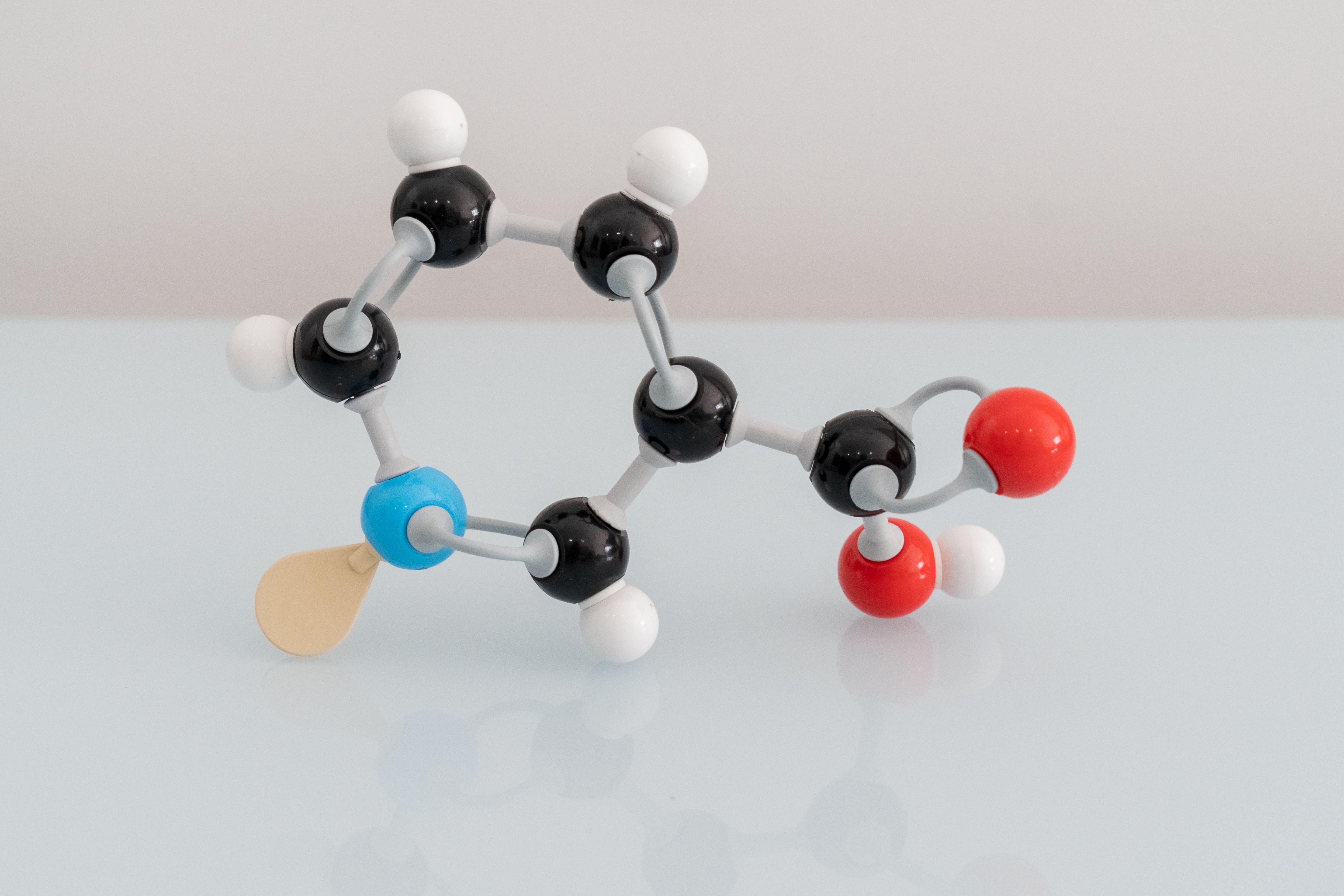 Isolated vitamin B3 made by molecular model with reflection on white background. Niacin chemical formula with colored atoms and bonds