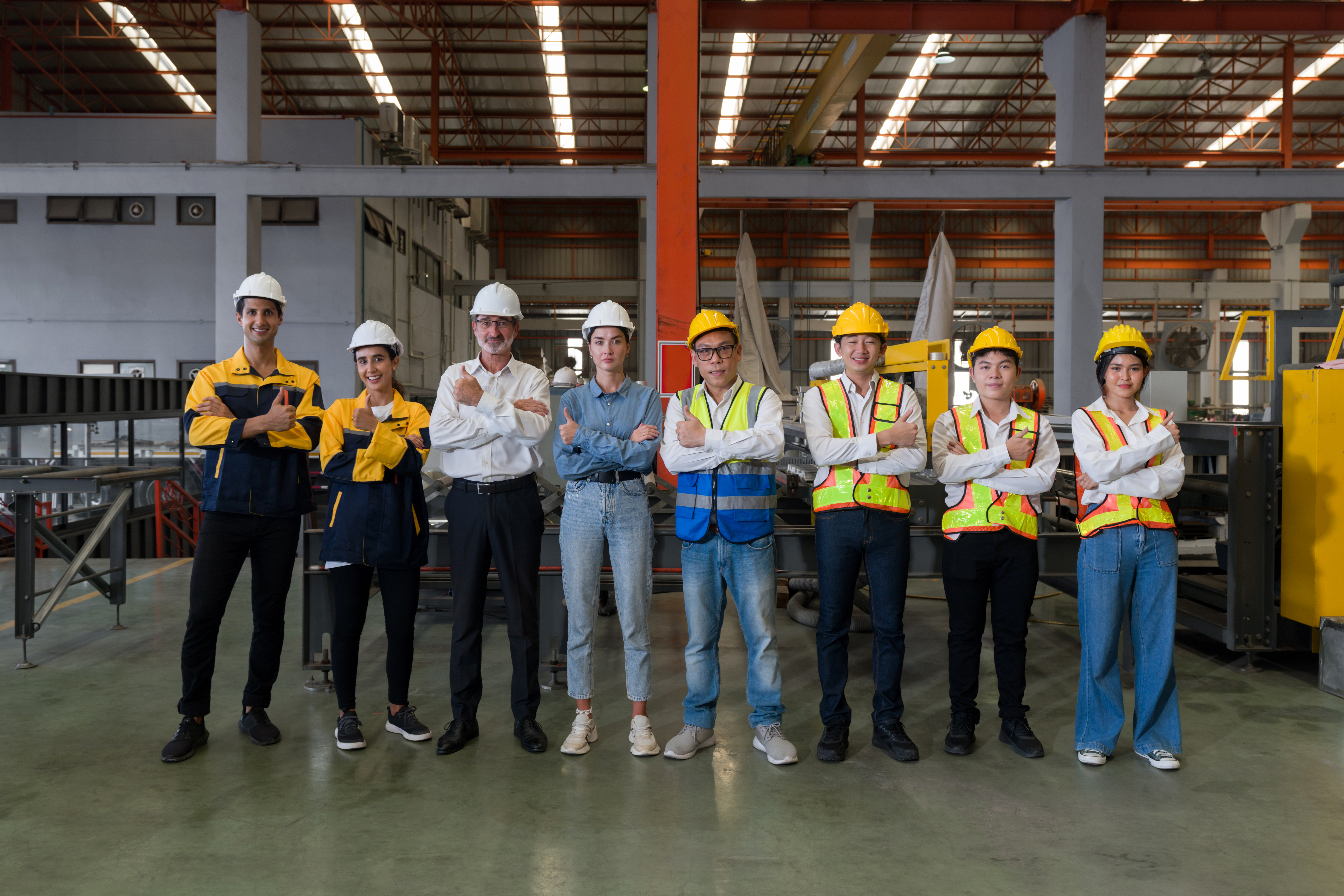 Industrial teamwork. Professionals donning safety hard hats standing together in a bustling factory.