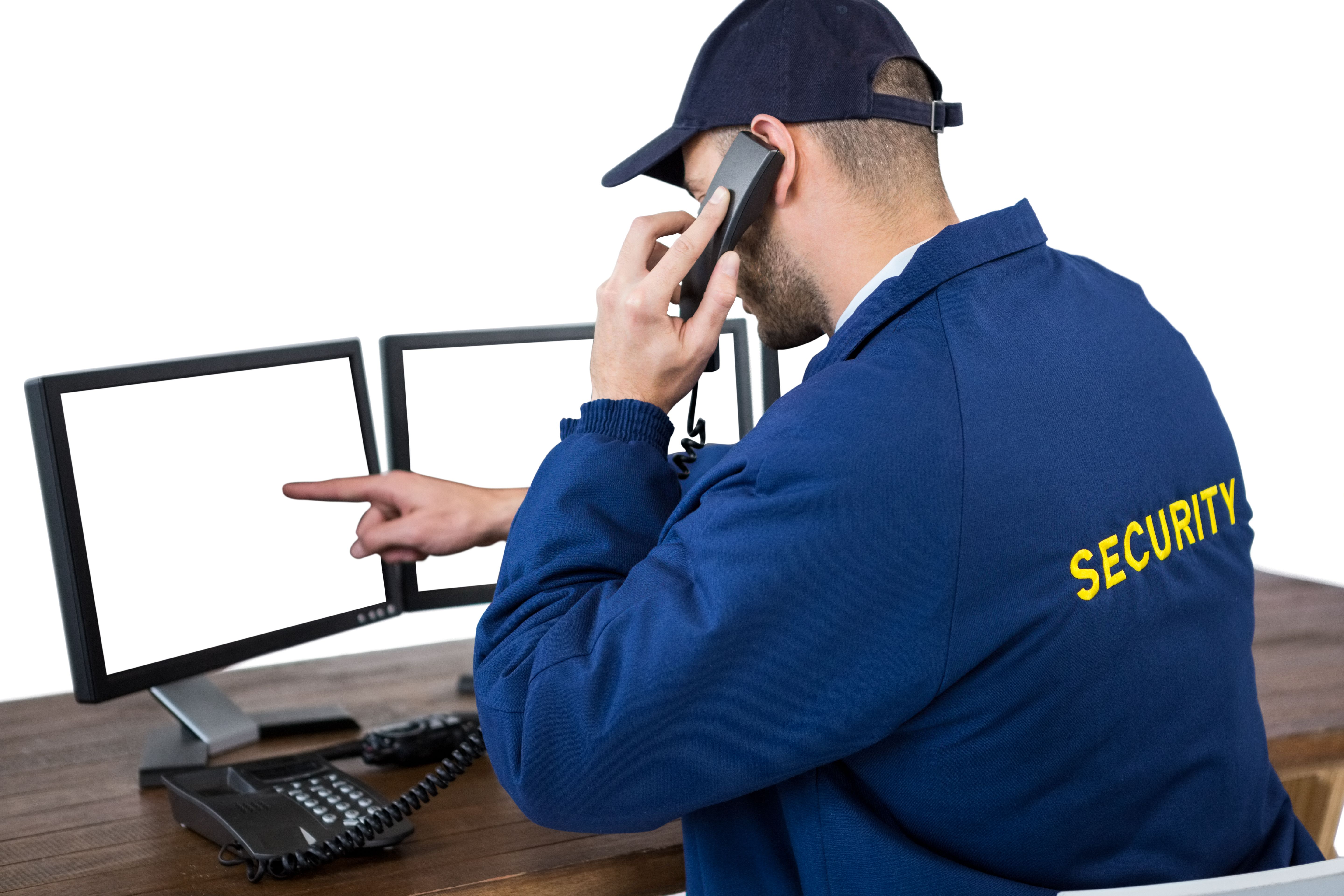 Security officer talking on phone while pointing at computer monitors Security officer talking on phone while pointing at computer monitors