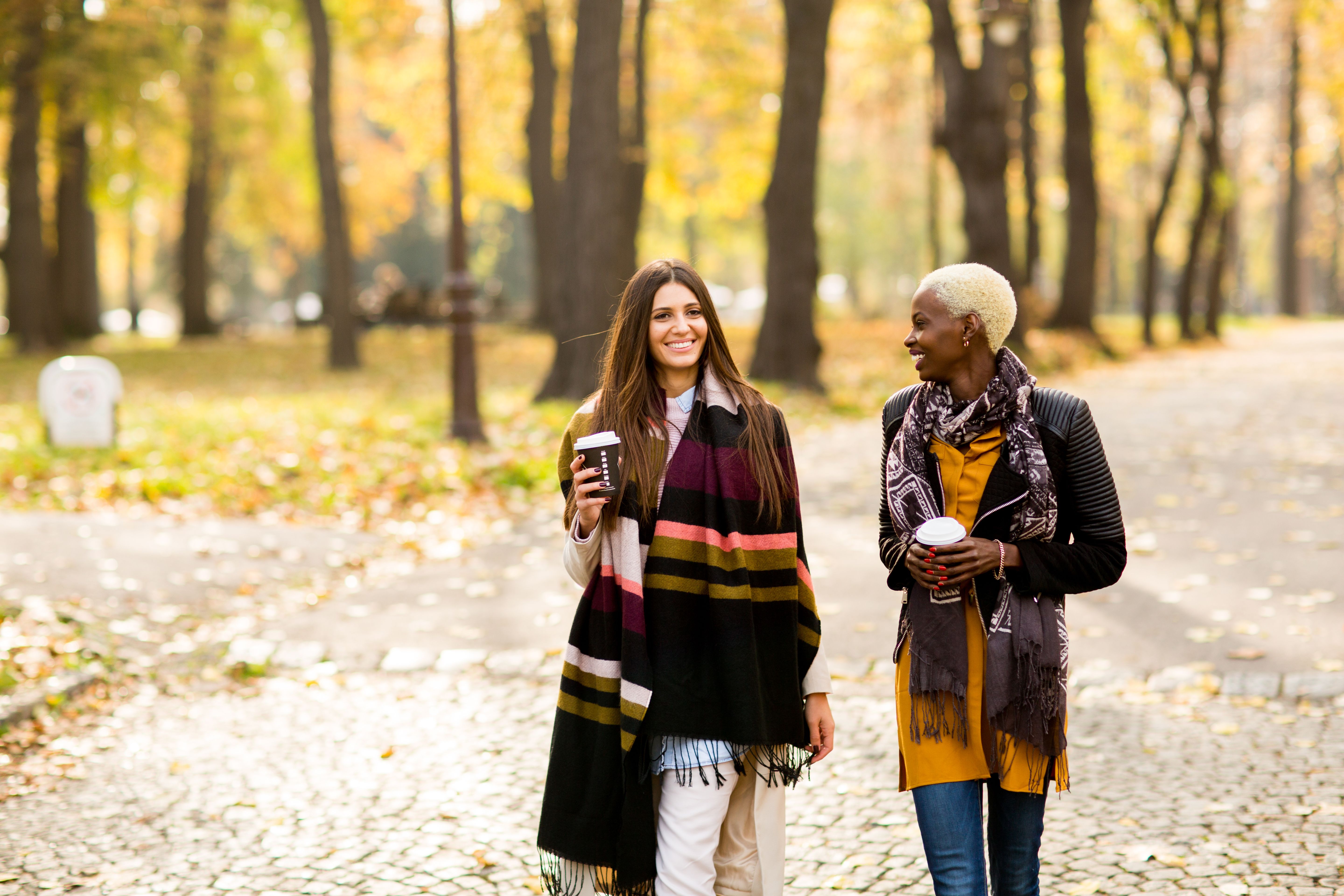 Two pretty young multiethnic female friends walking in park