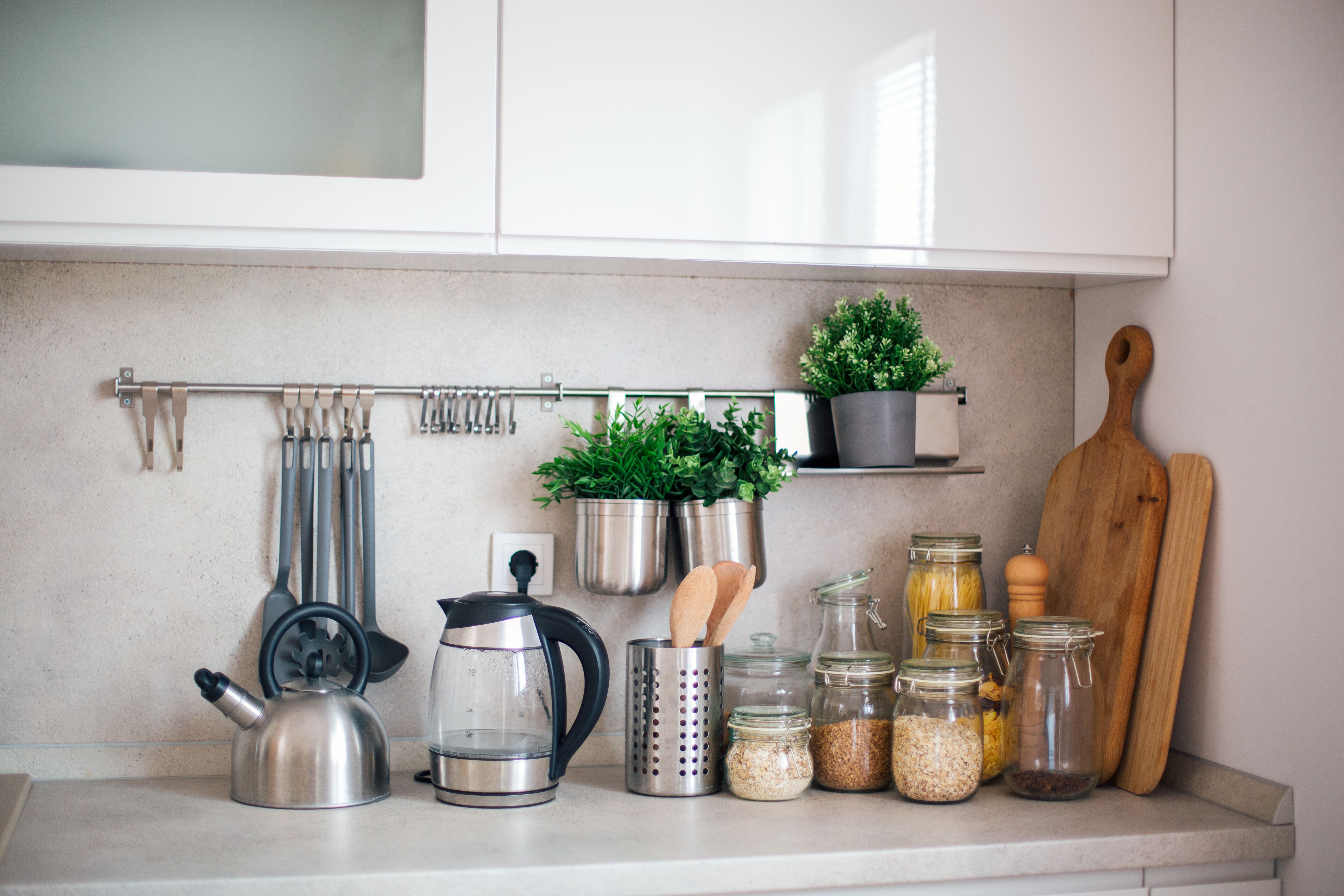 Modern kitchen countertop with utensils, plants and dry food jars
