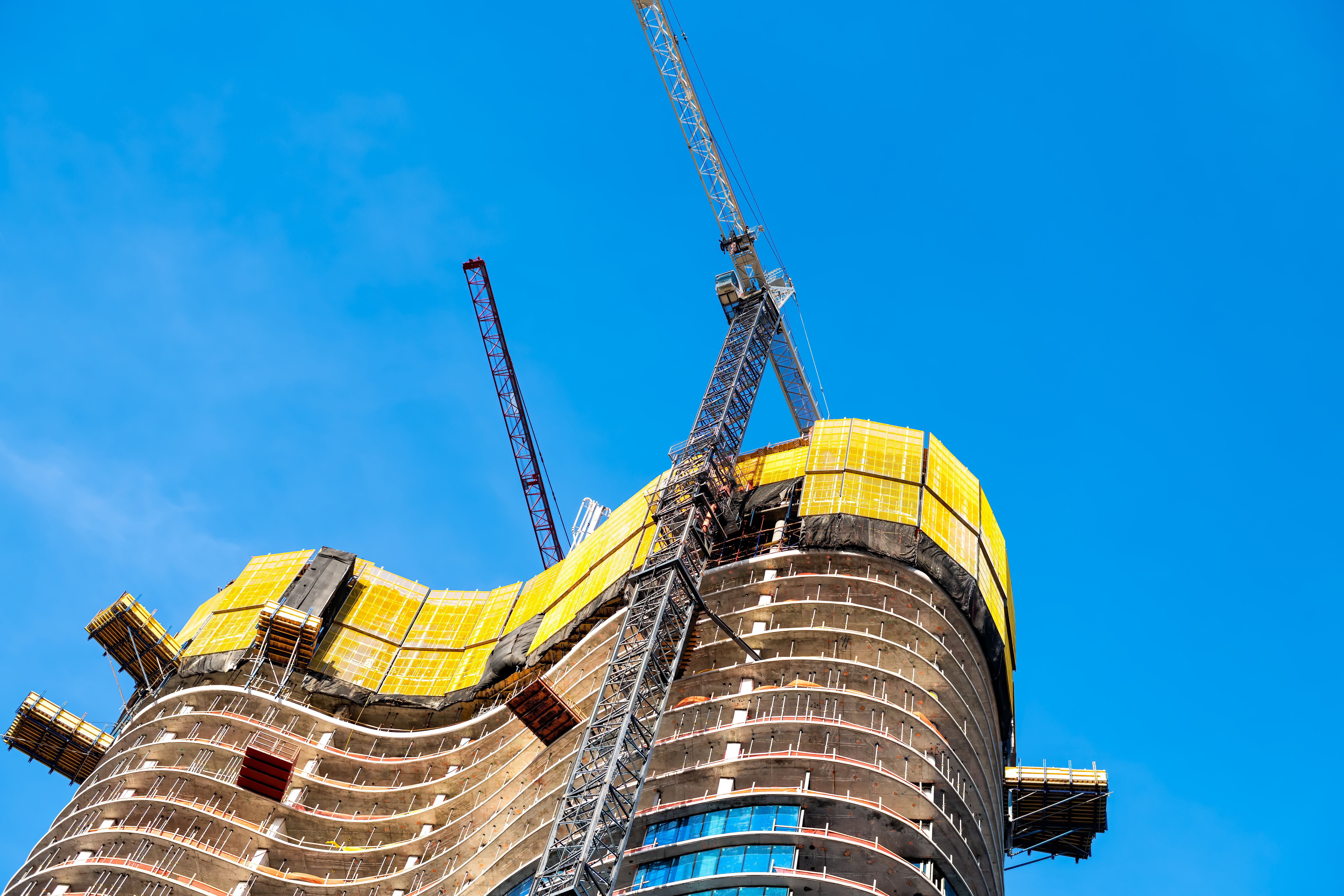 Construction site with cranes building tower skyscraper structure exterior isolated against blue sky in Miami, Florida