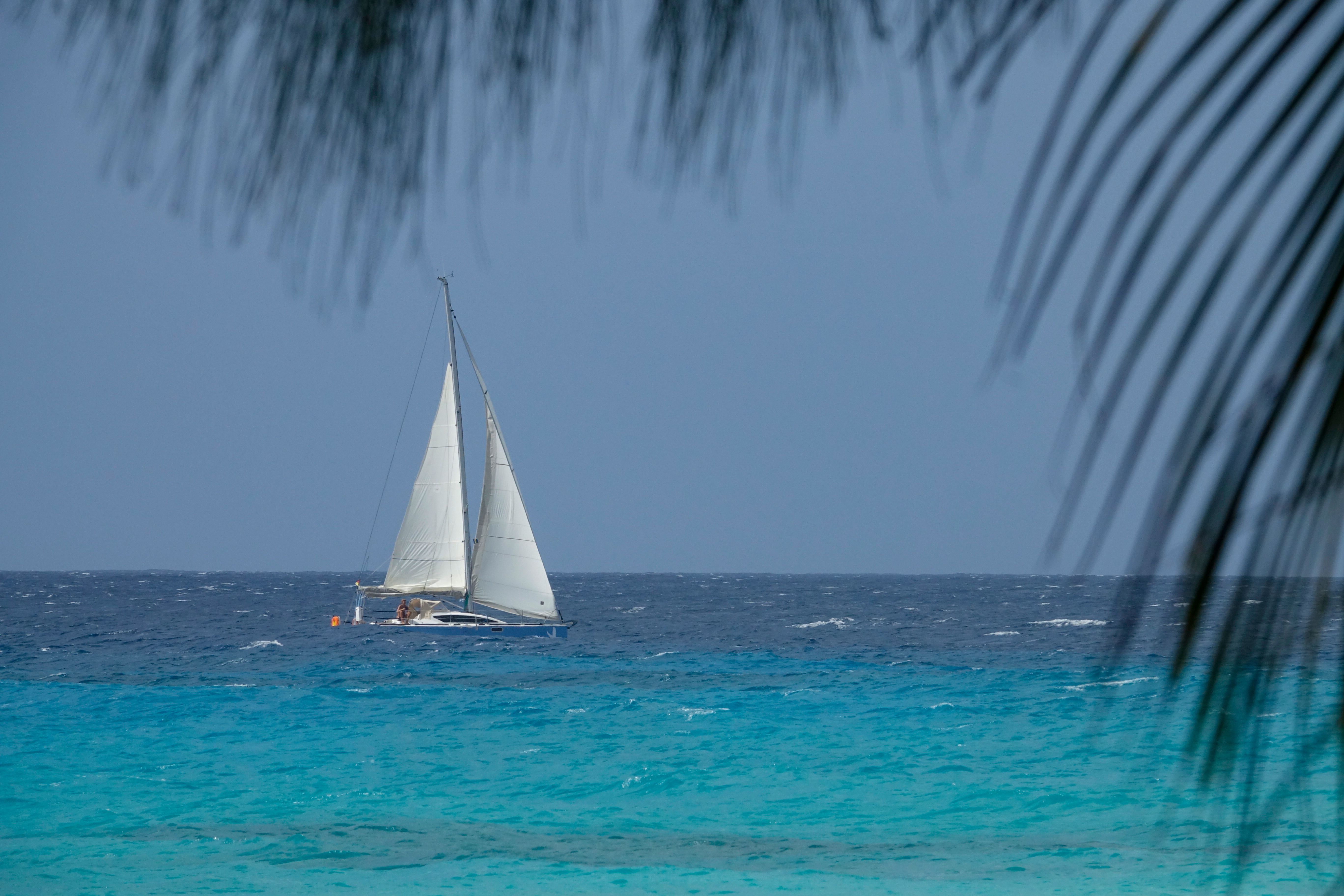 CLOSE UP: Sailboat navigates the tranquil turquoise ocean on a cloudy summer day CLOSE UP: Sailboat navigates the tranquil turquoise ocean on a cloudy summer day