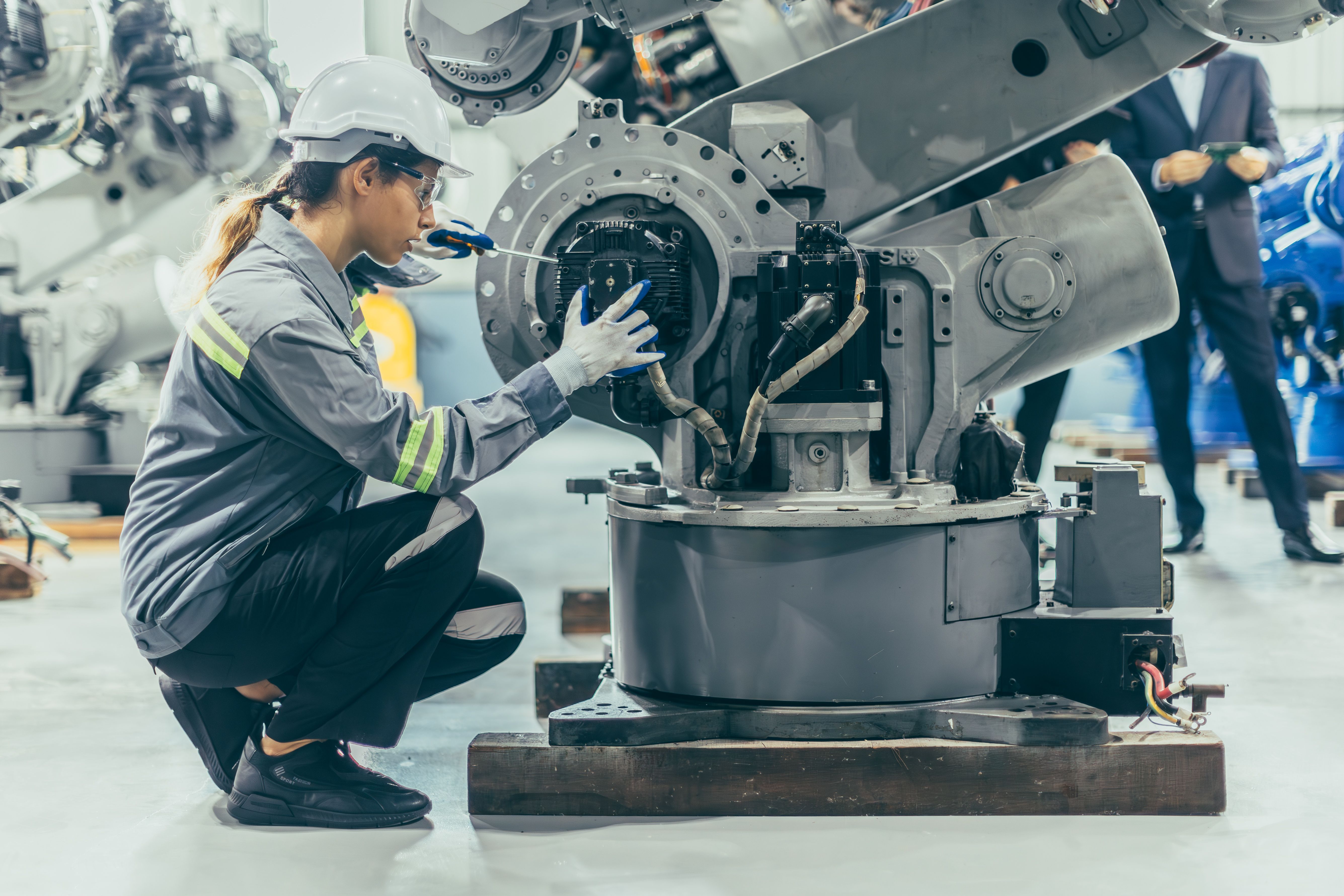 Engineer robotic mechanic women technician working in advance robotic industry plant work assembly robot arm repair fix maintenance or service large machine by hand skill
