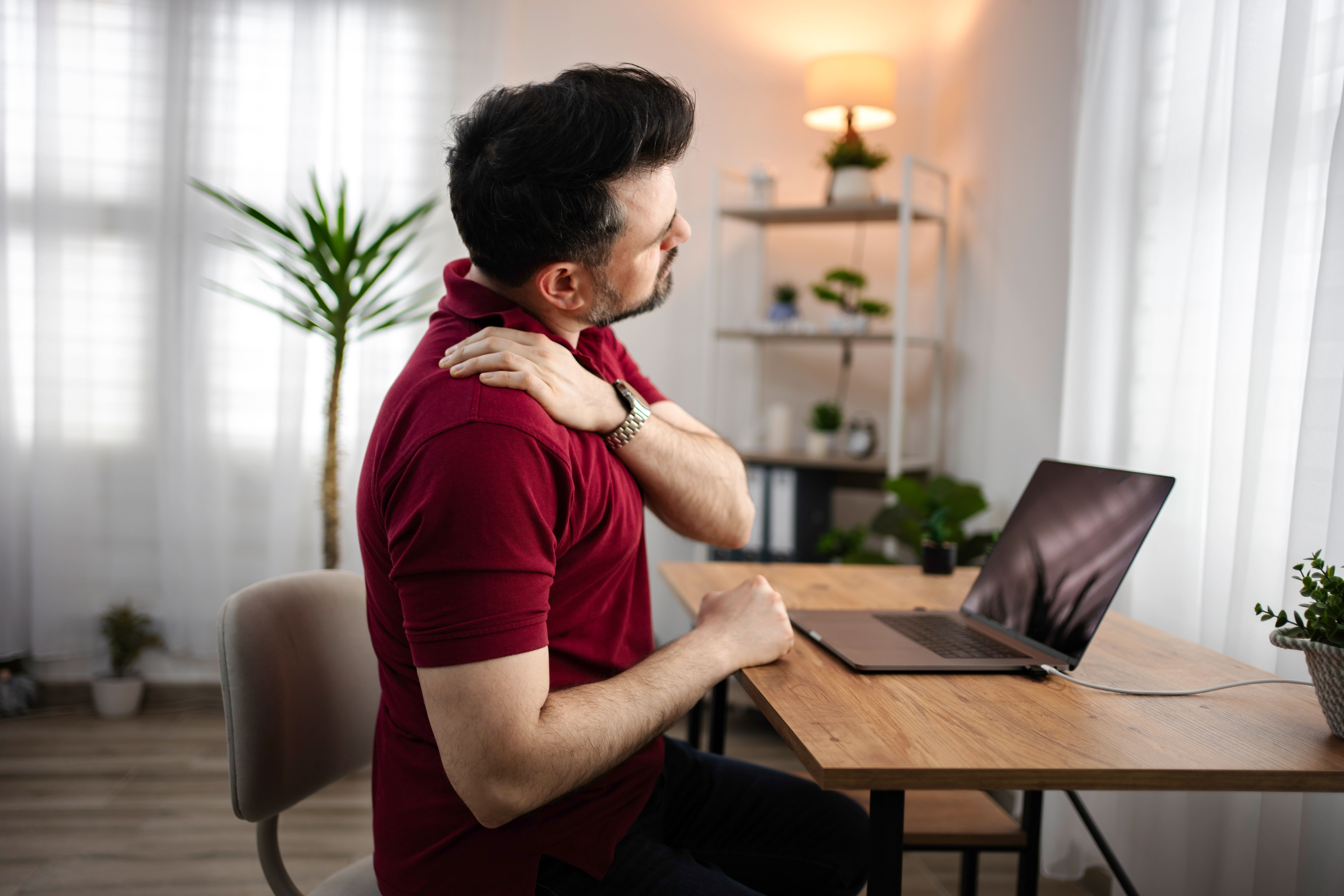 Homem que sofre de dor no ombro e no pescoço enquanto trabalha em casa