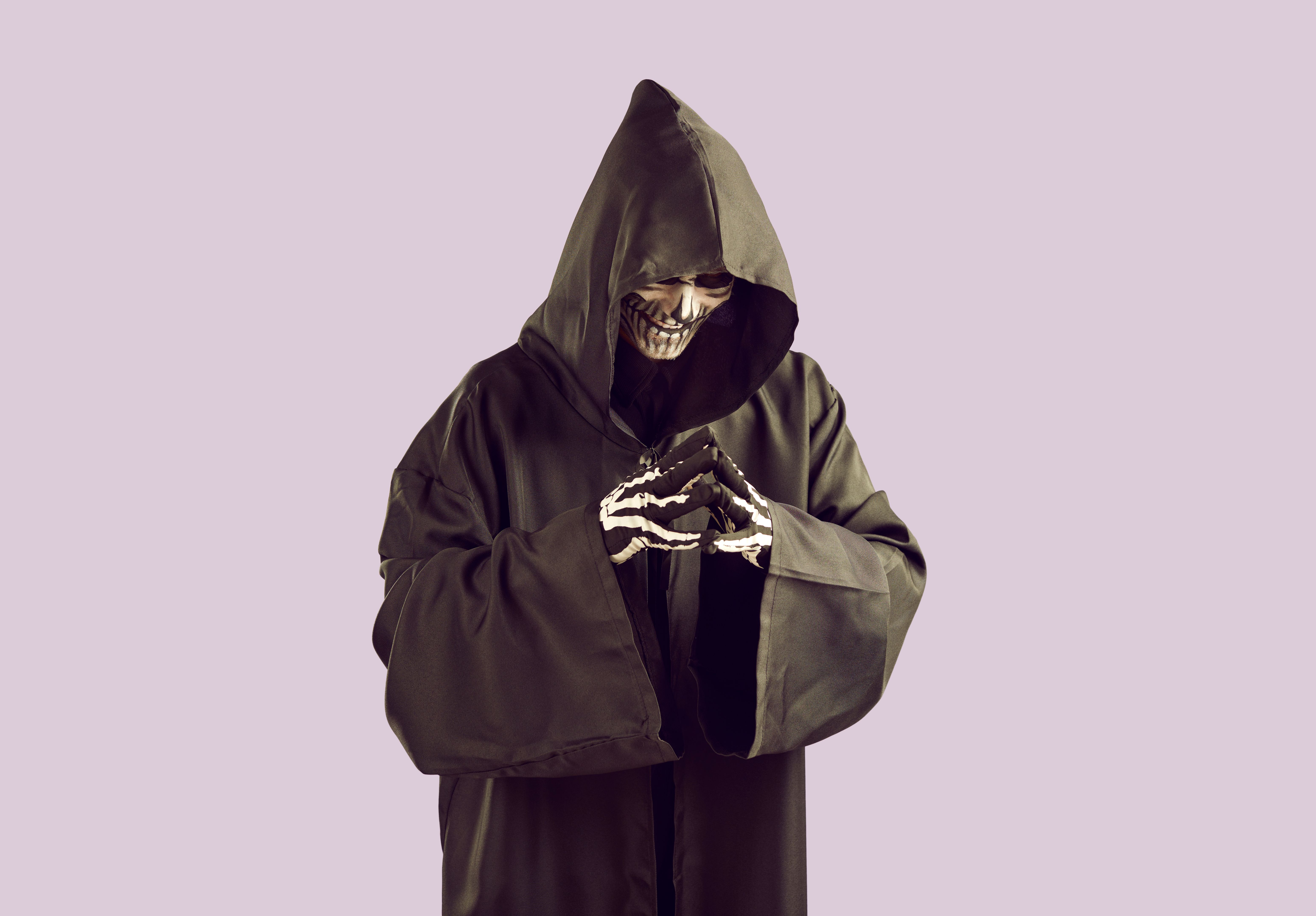 Grim reaper is planning something bad and is smiling ominously while gesturing with his fingers.