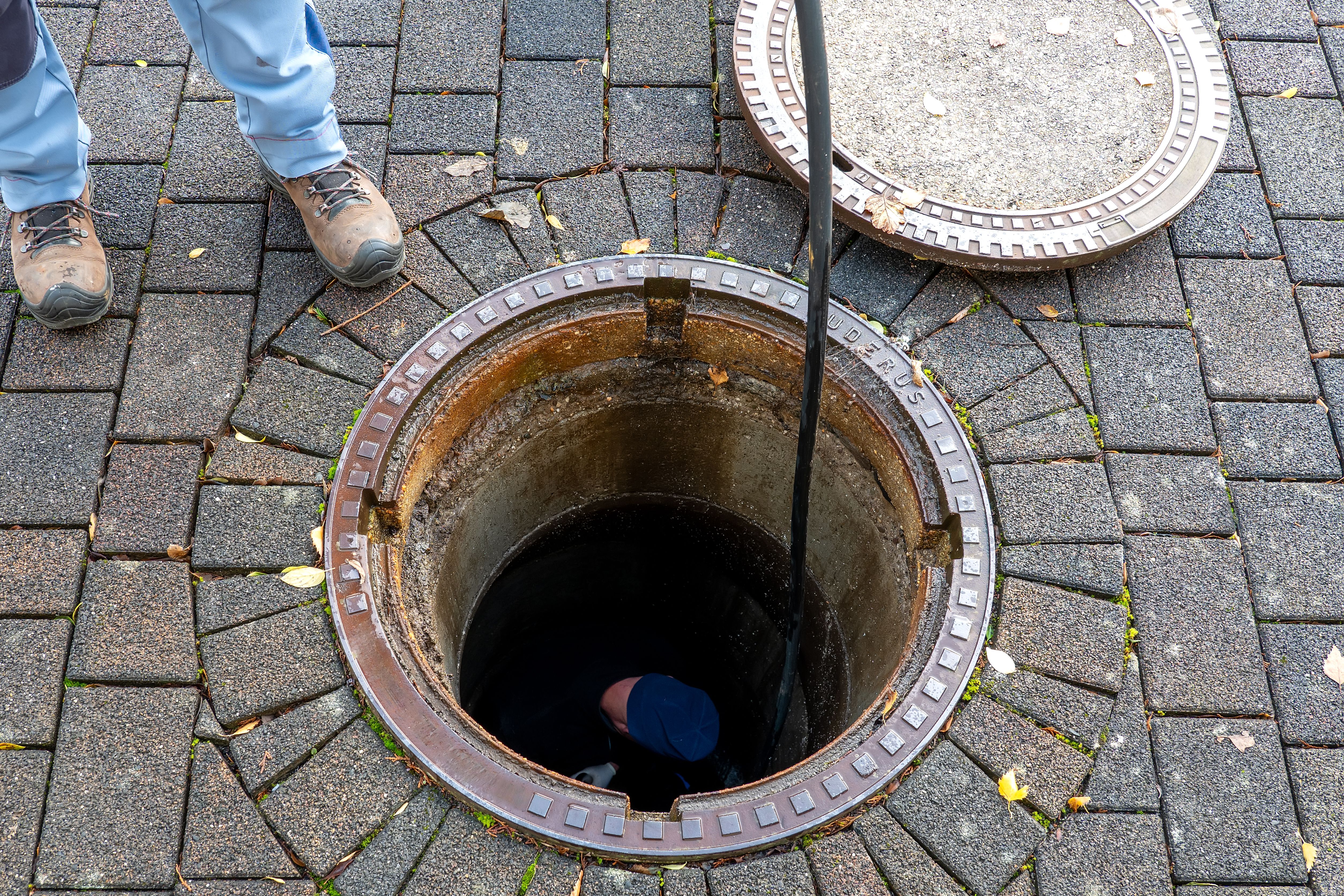 Blocked pipe. Sewer inspection with camera. Sewer cleaning company worker at work in a manhole