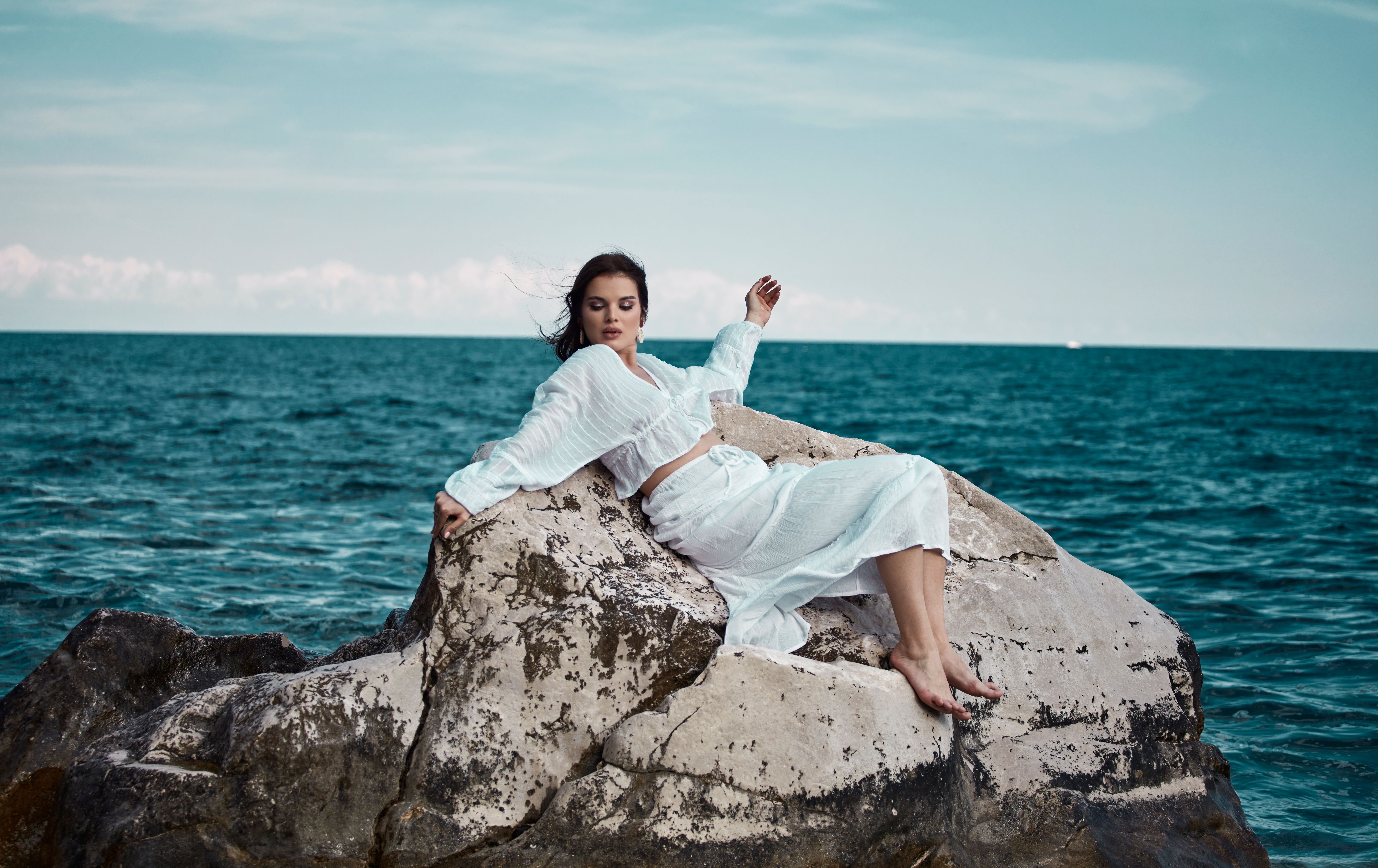 Young woman lying on a rock in the middle of the sea, having a pleasant time.
