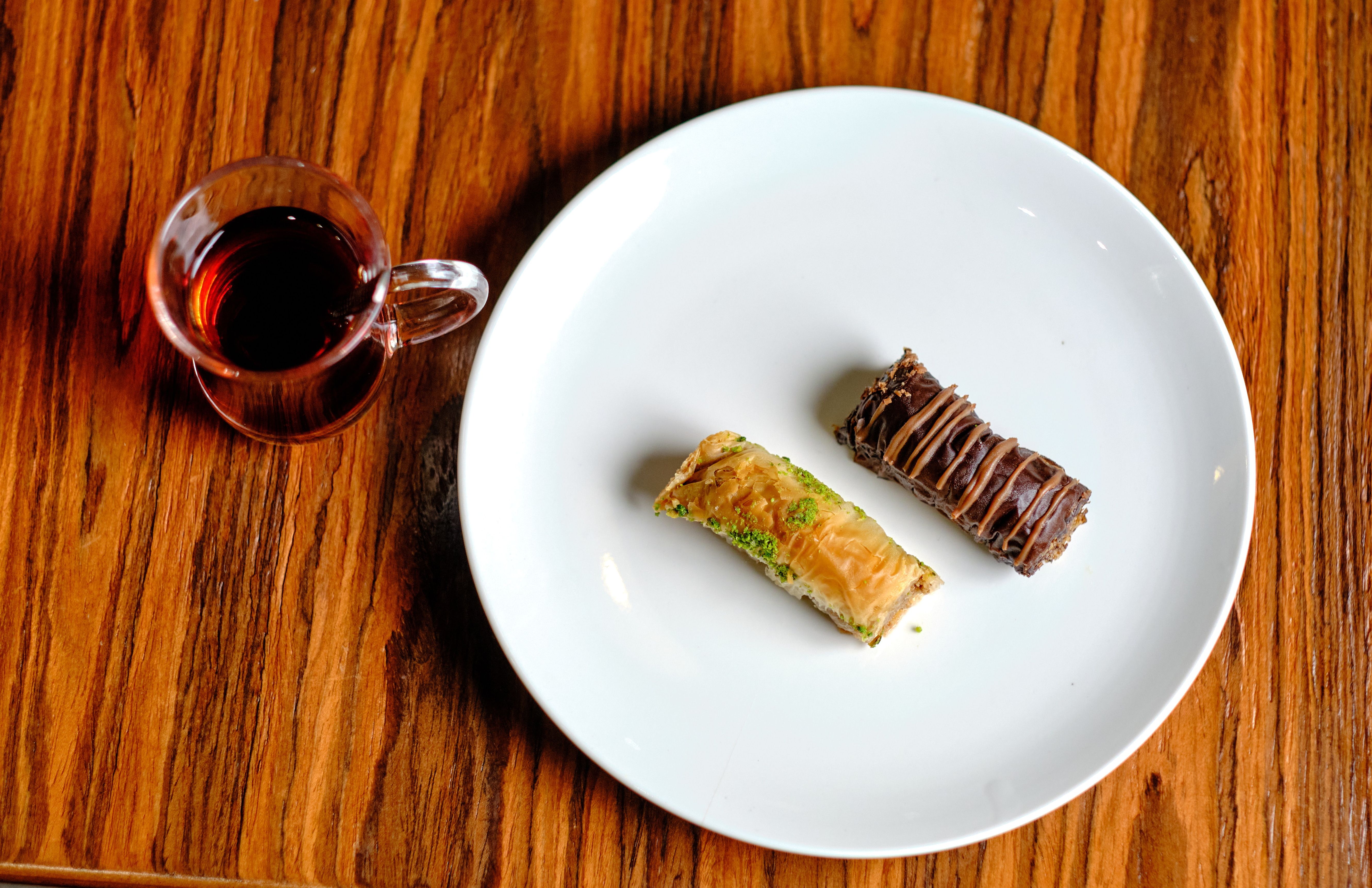 On a white plate are two pieces of Turkish baklava: classic and chocolate.