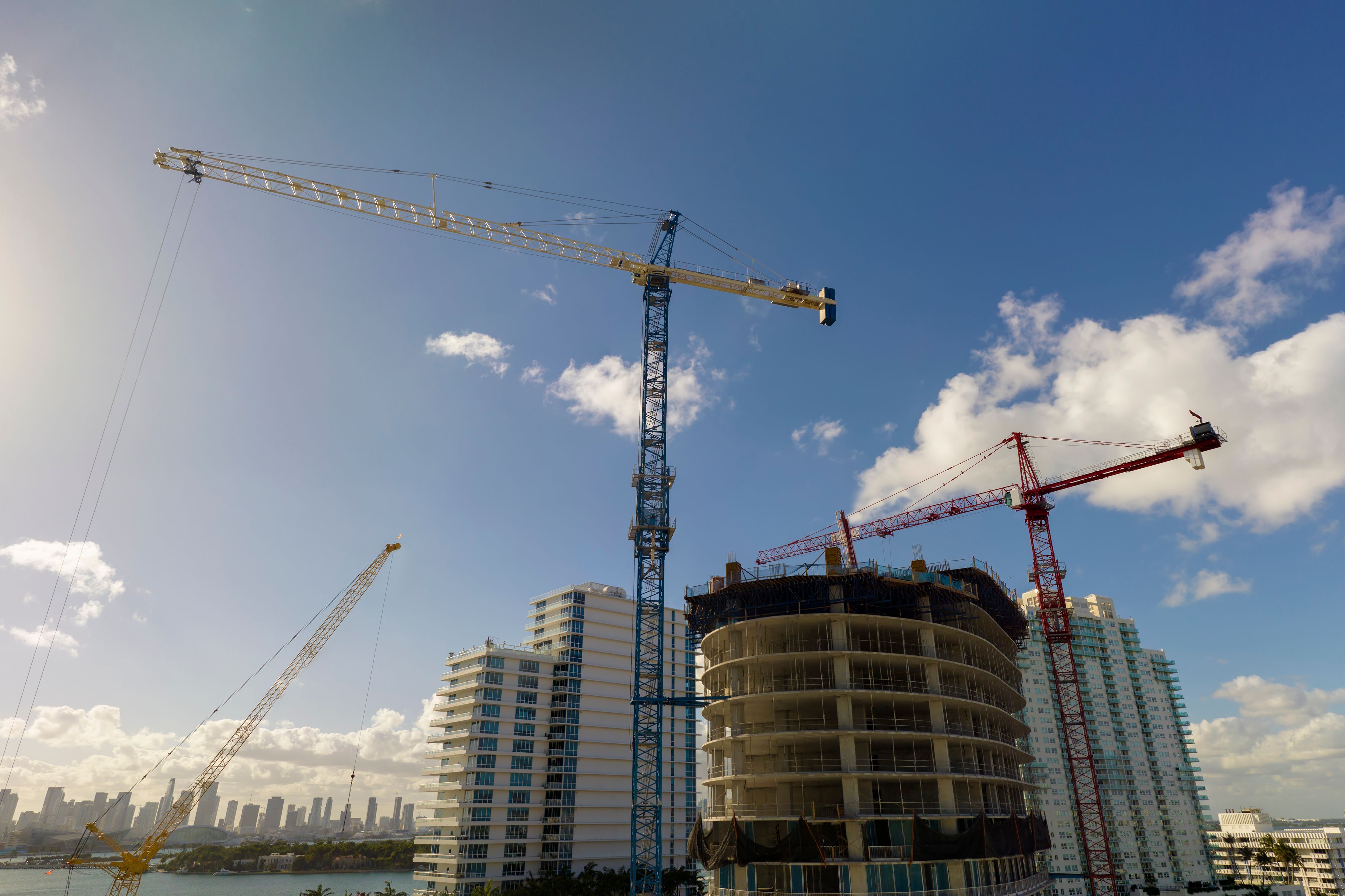 Aerial view of new developing residense in american urban area. Tower cranes at industrial construction site in Miami, Florida. Concept of housing growth in the USA