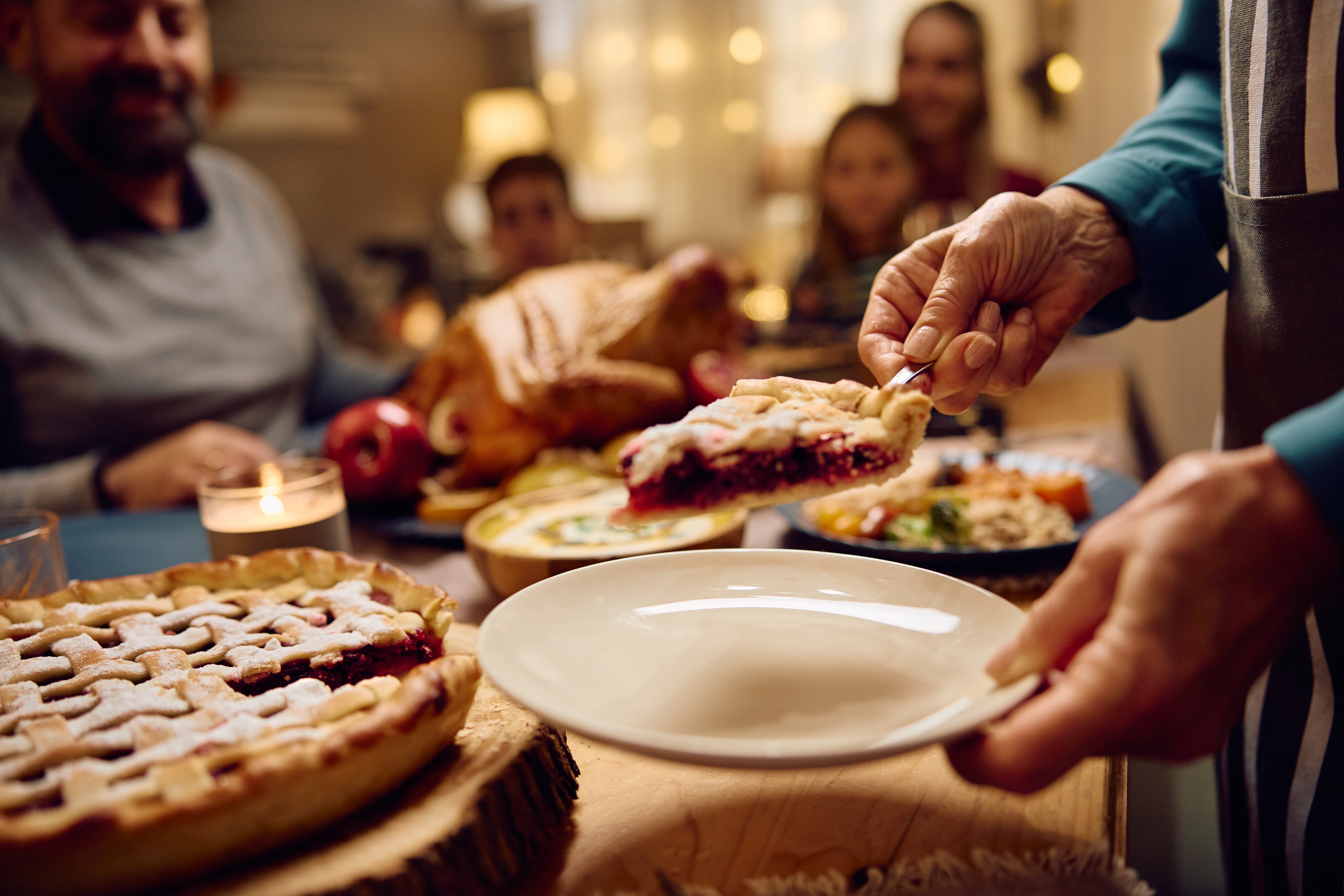 Close up of grandmother serving a slice of sweet pie on Thanksgiving.