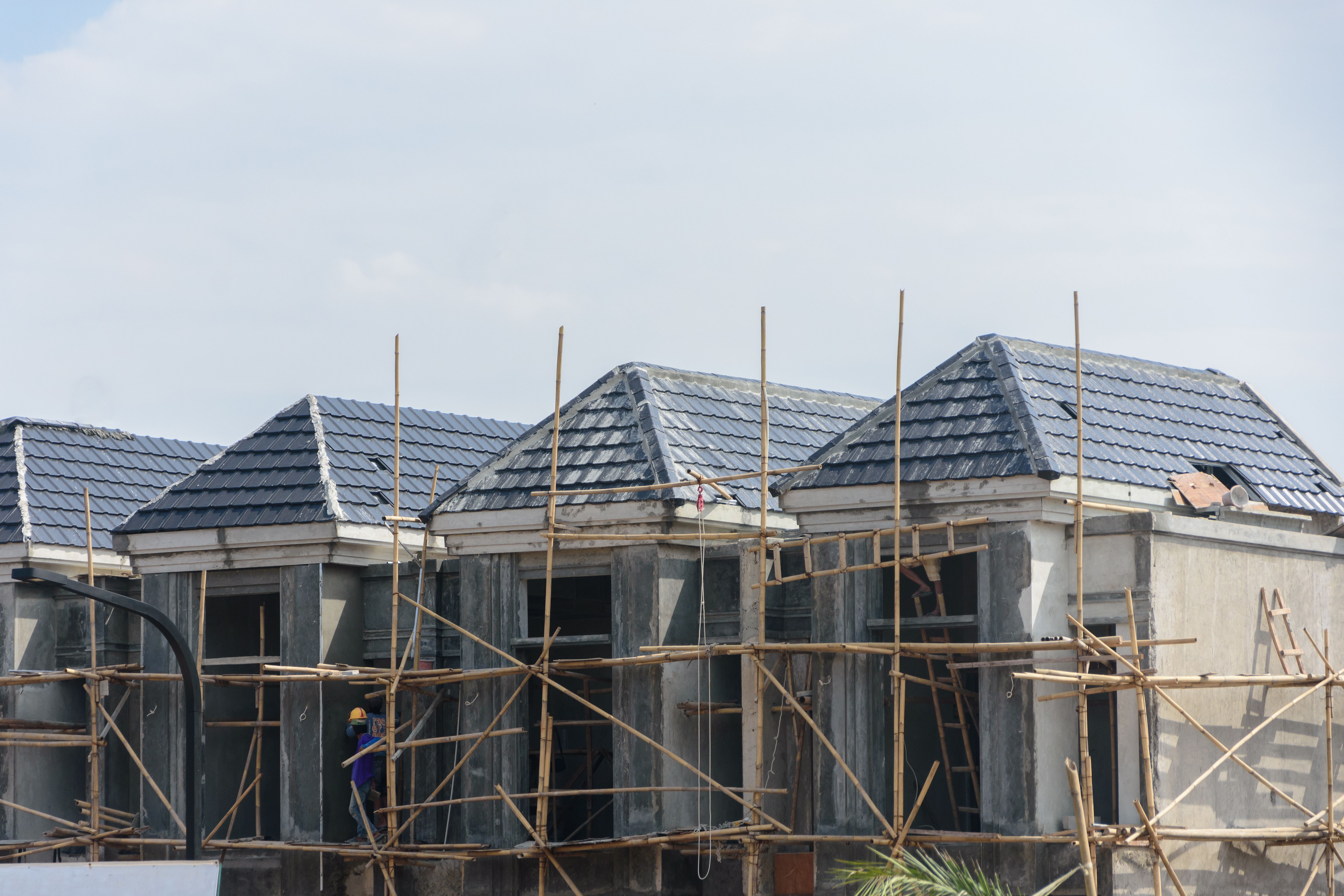 Row of new residential houses under construction with traditional bamboo scaffolding