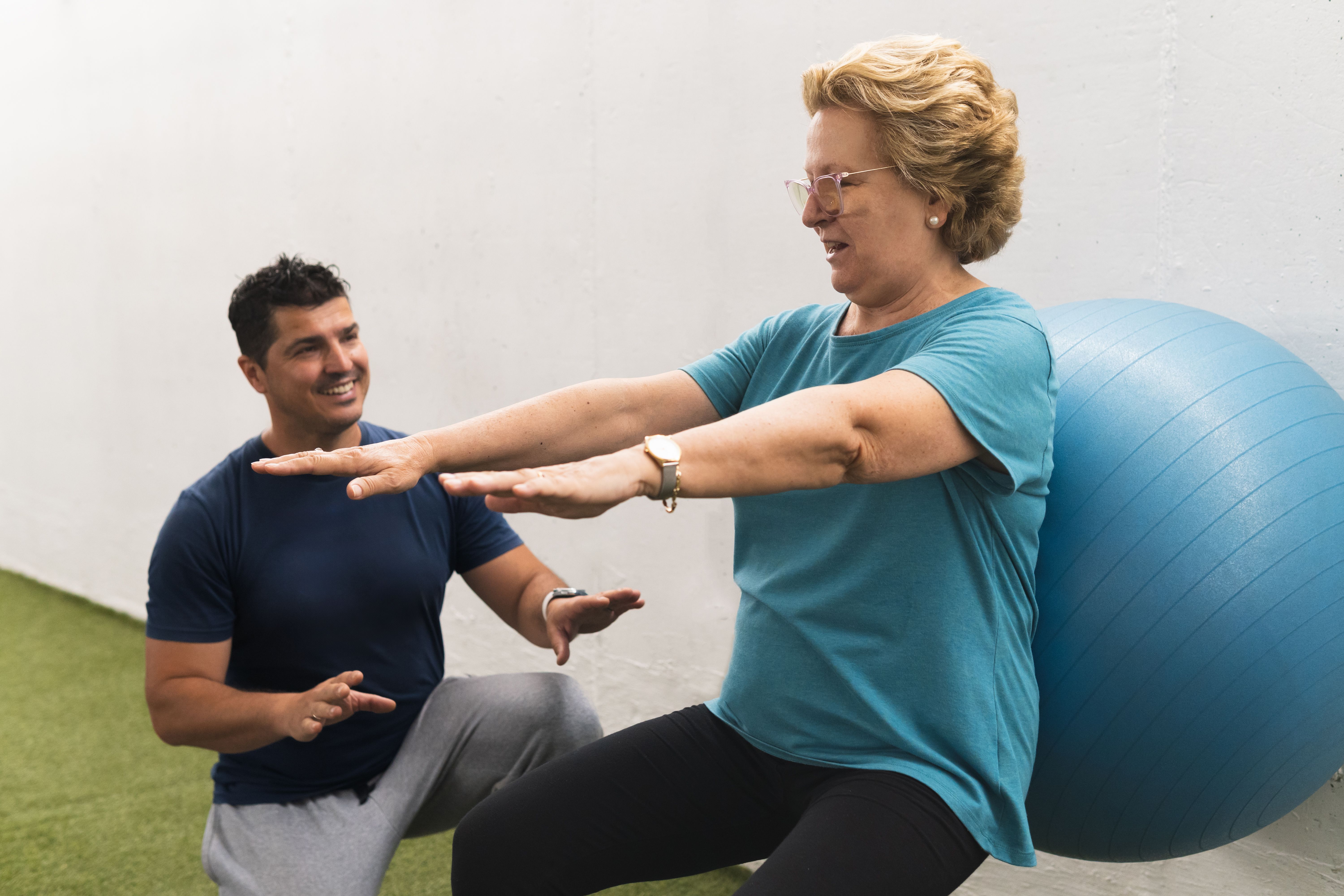 Older patient exercising with her personal trainer. Lifestyles concept.