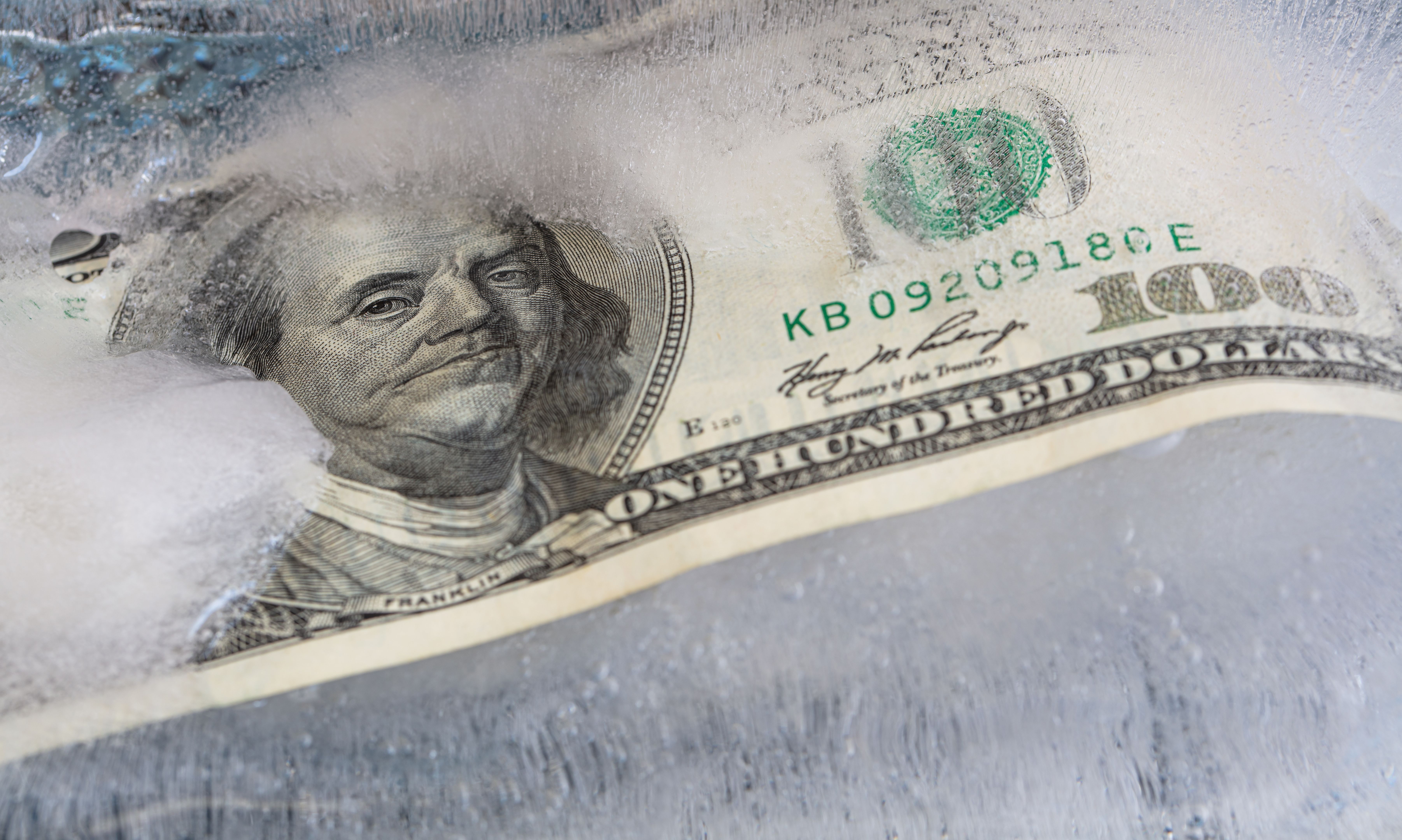 100 US dollar frozen under a layer of ice