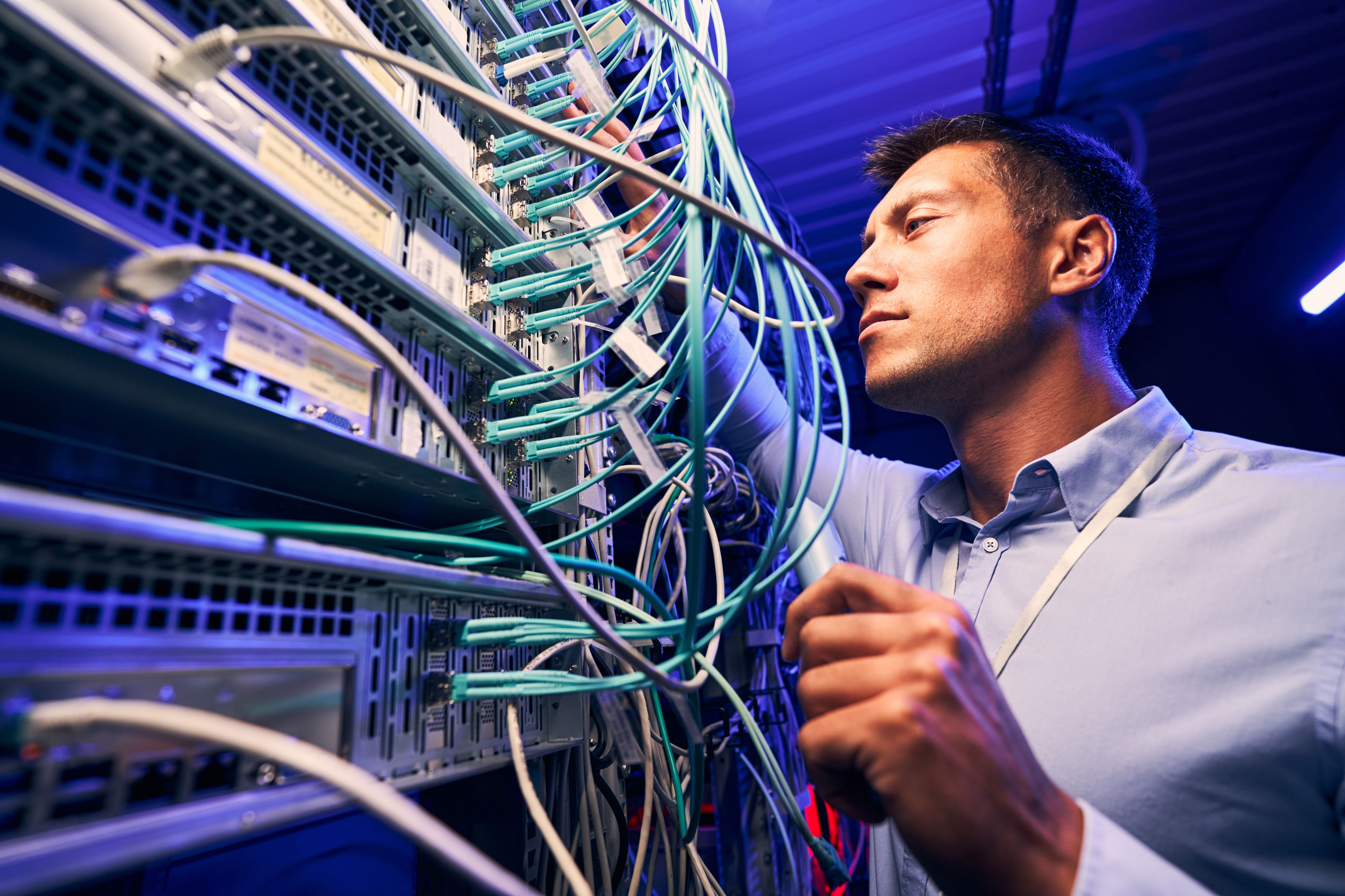 Engineer testing cable connections on network server, ensuring connectivity.