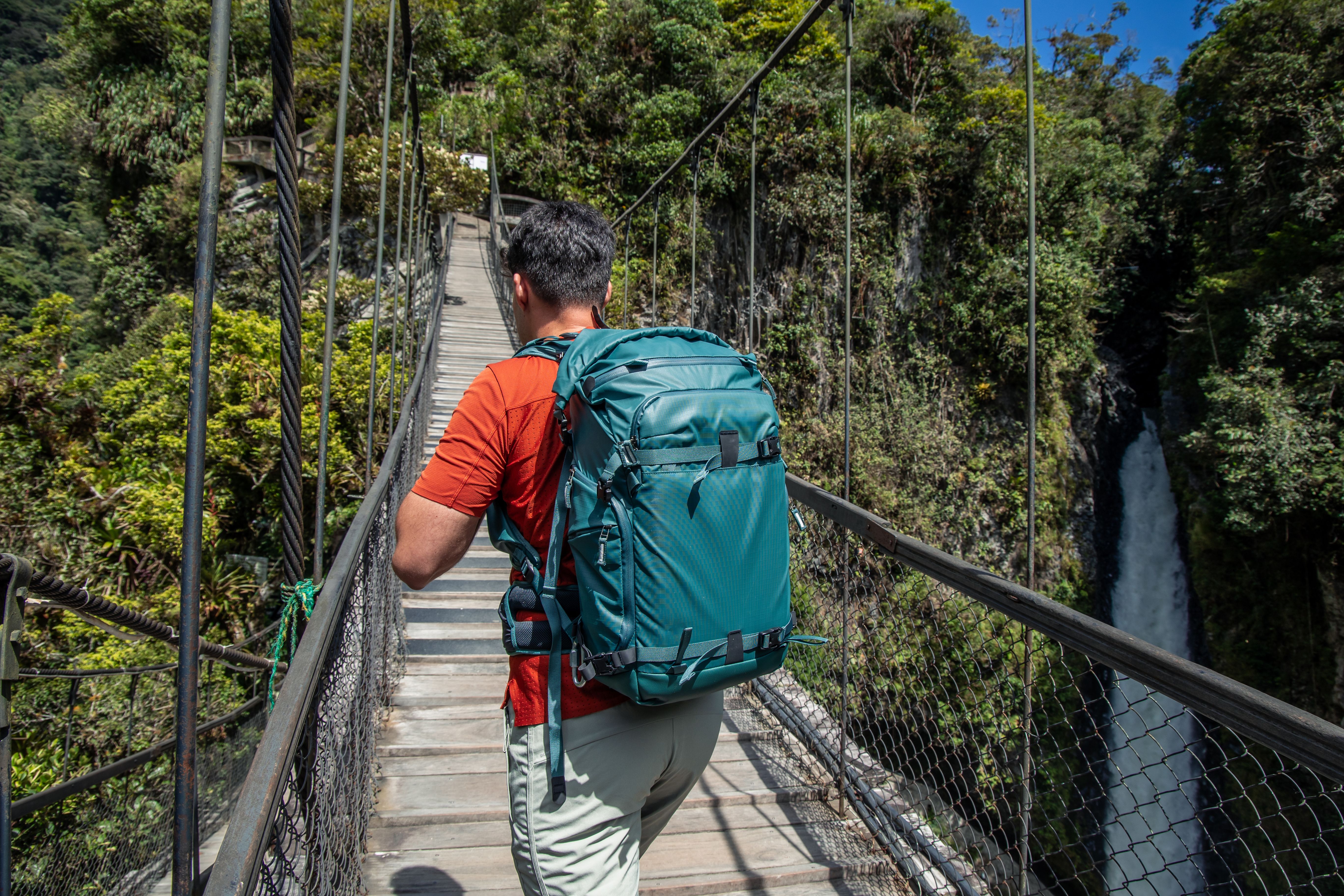 explorer Crossing Hanging Wooden Bridge at Pailon del Diablo Waterfall, Baños de Agua Santa, Ecuador explorer Crossing Hanging Wooden Bridge at Pailon del Diablo Waterfall, Baños de Agua Santa, Ecuador