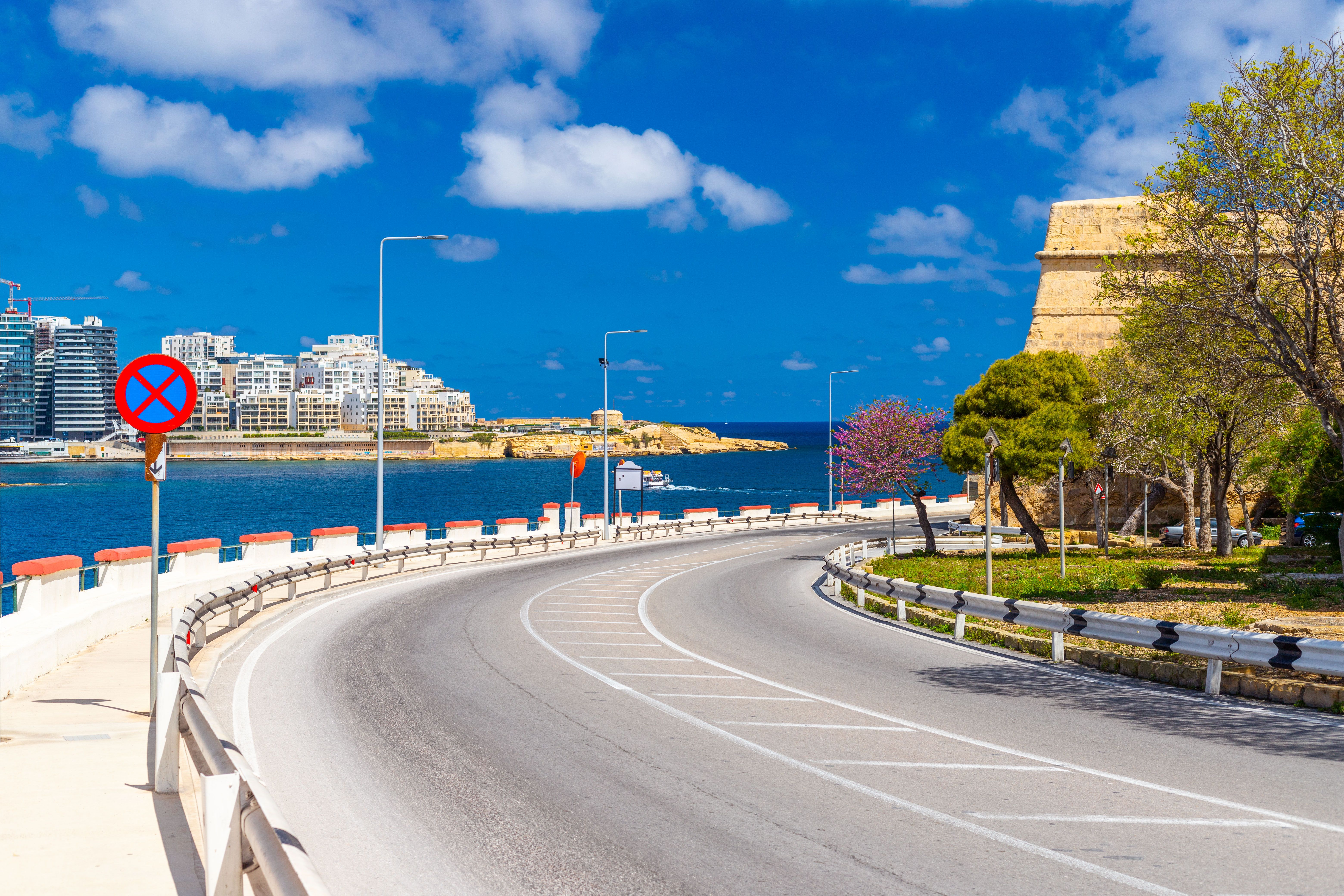 Empty coastal road around the walled town of Valletta, Malta. The town of Sliema in the background