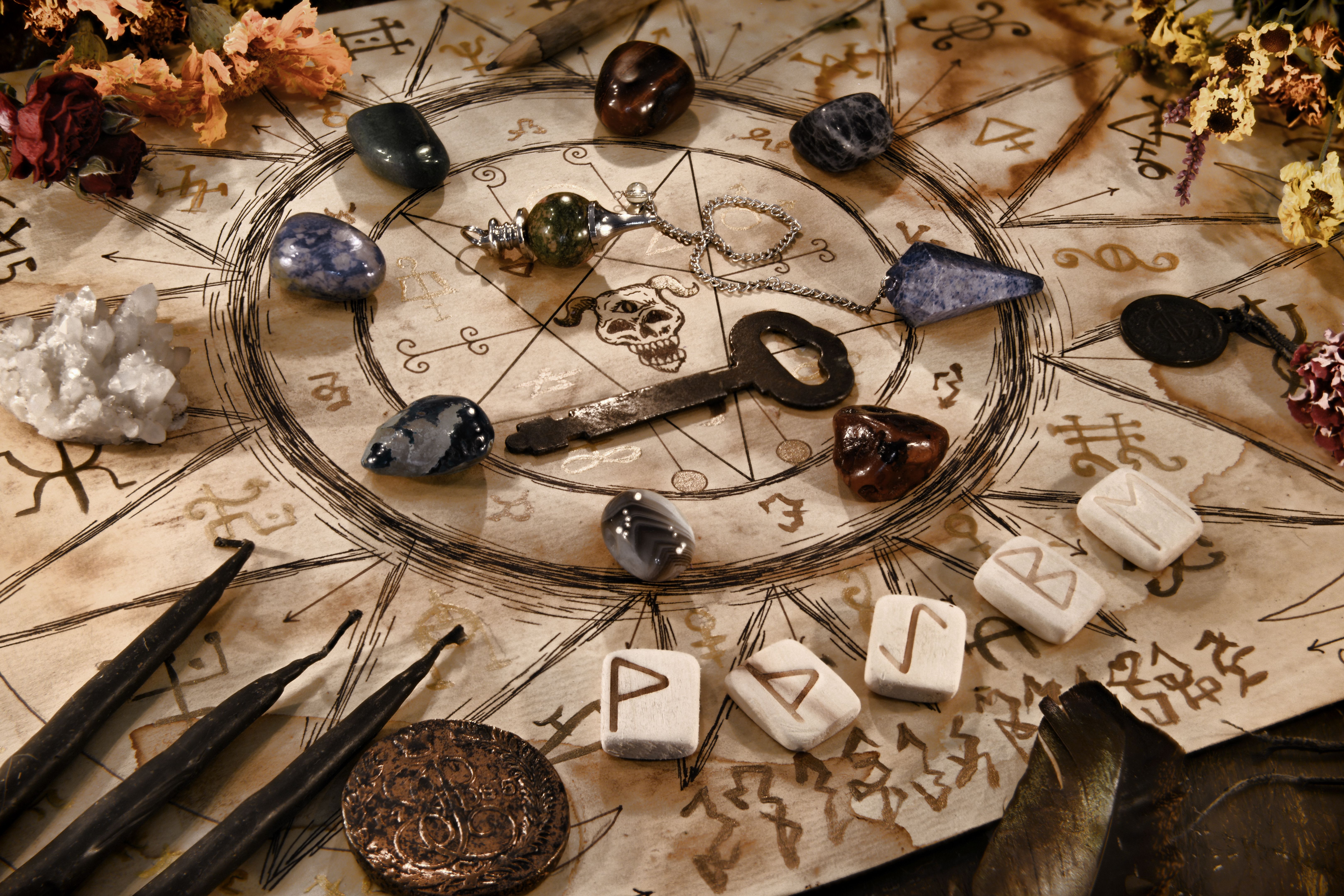Manuscript with witch drawings, key, black candles and runes.