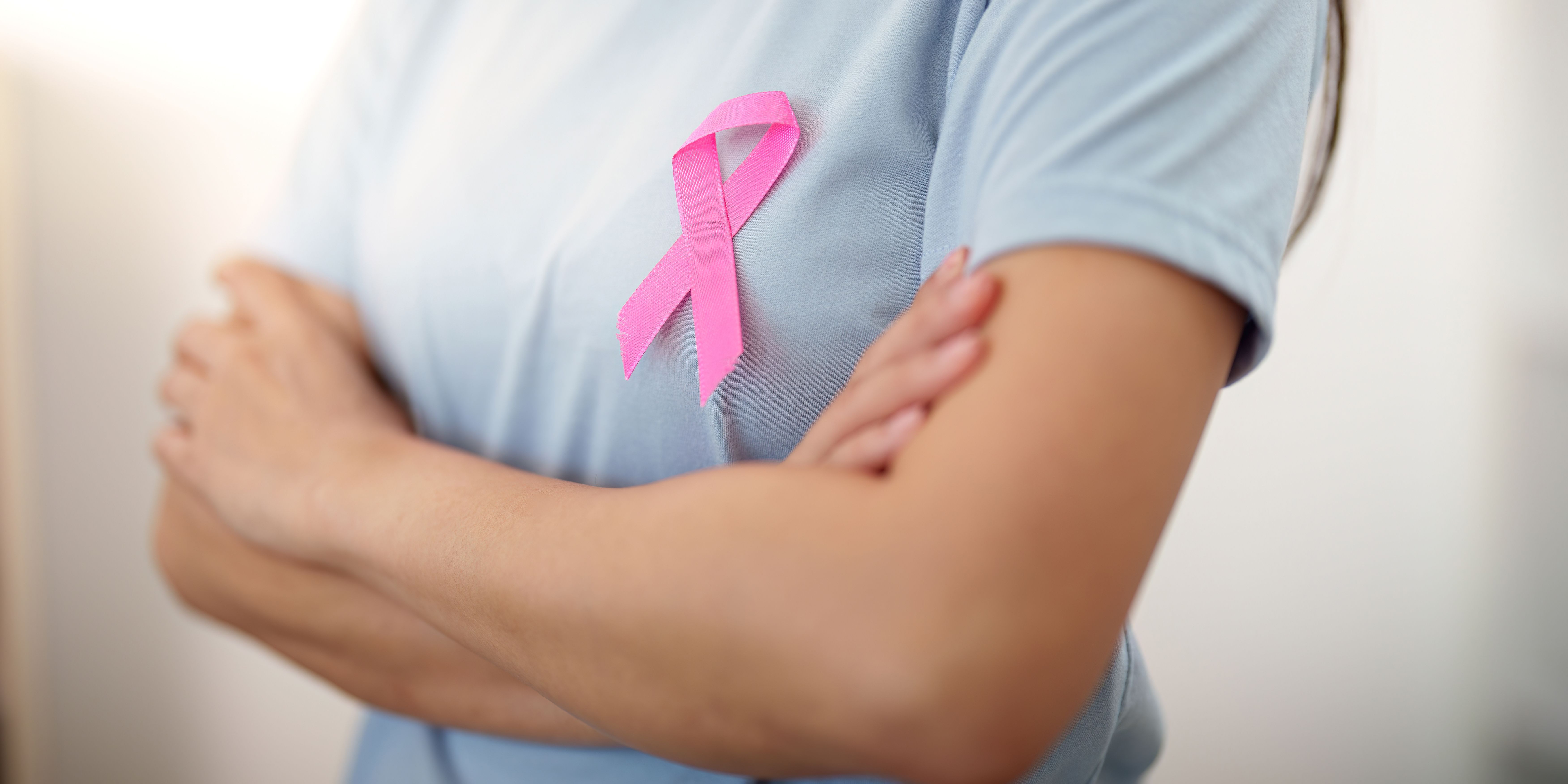 Breast Cancer Awareness. Woman displaying pink ribbon symbol on her shirt. Breast Cancer Awareness. Woman displaying pink ribbon symbol on her shirt.