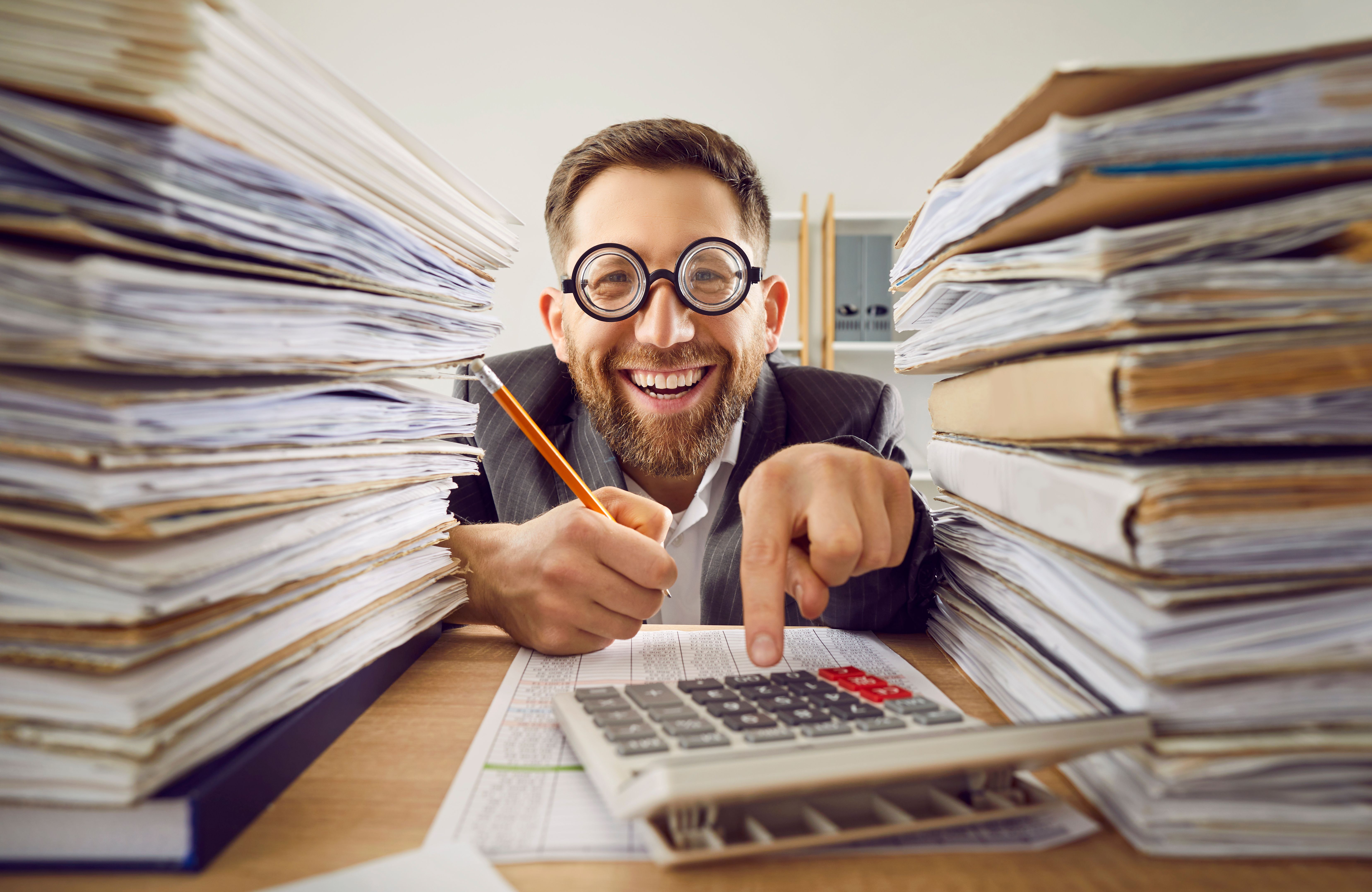 Business man working at the desk in office with a pile of folders and a stack of papers. Business man working at the desk in office with a pile of folders and a stack of papers.