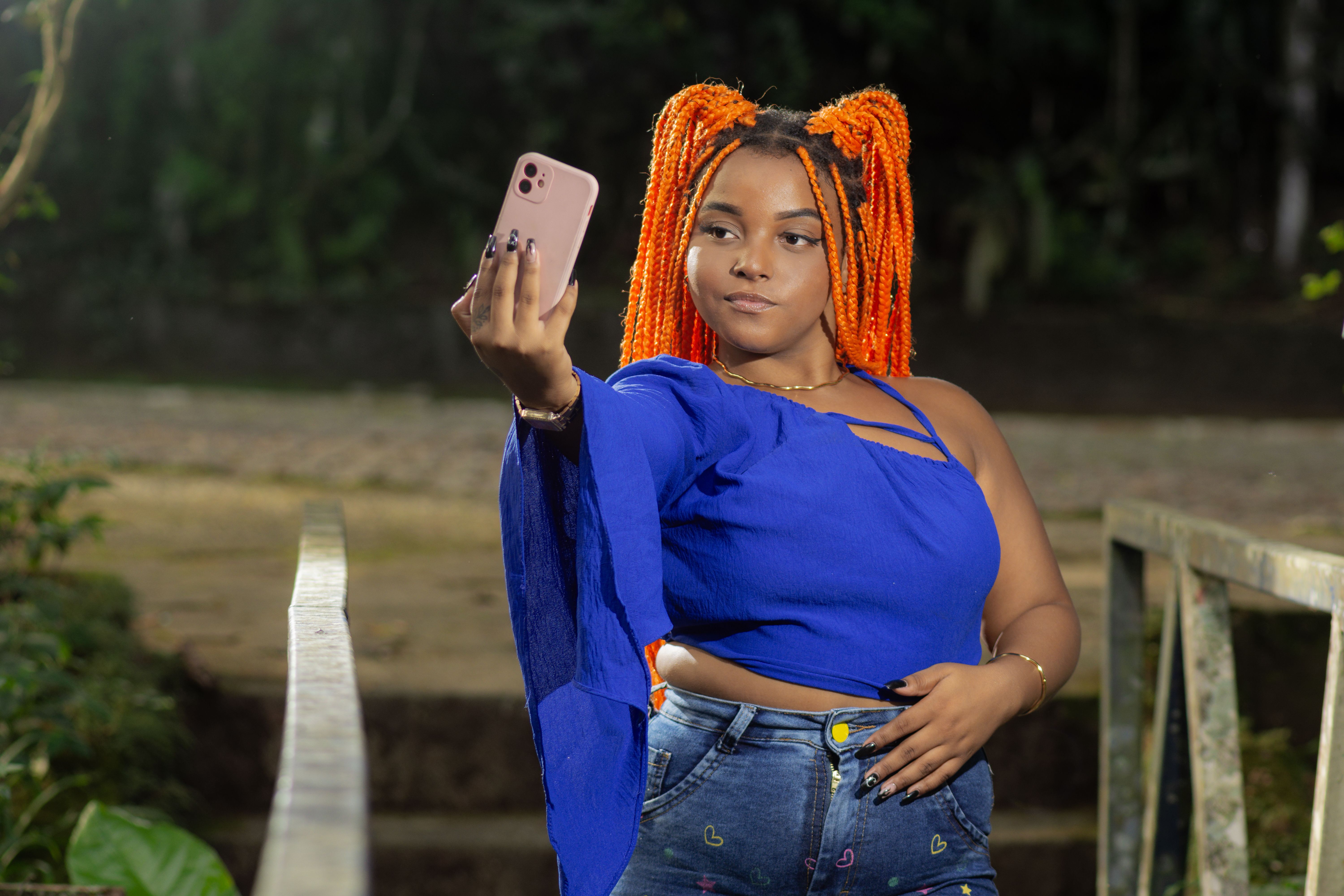 Black woman social influencer recording on cell phone. Content creator and digital influencer.