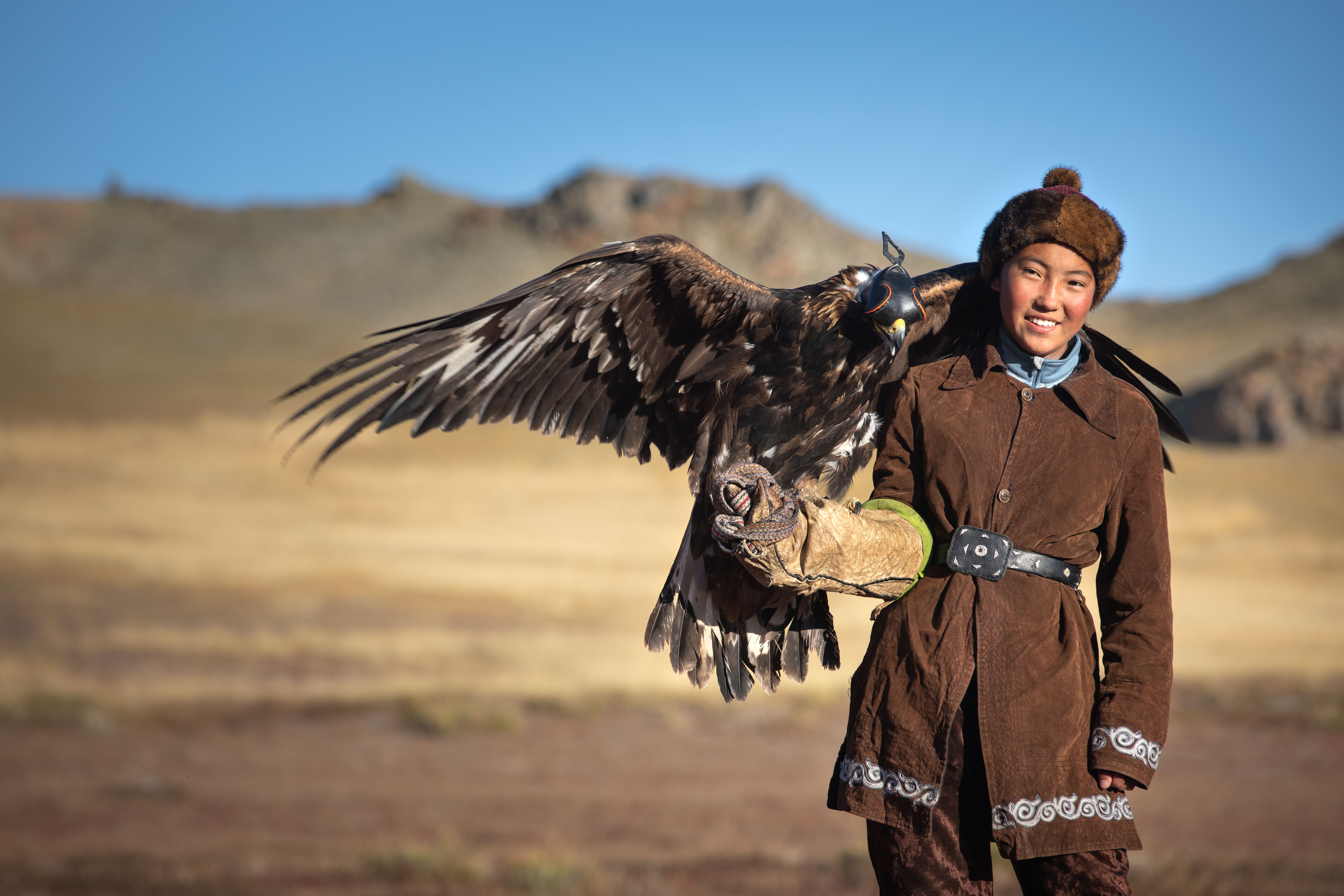 Young kazakh eagle hunter with his golden eagle.