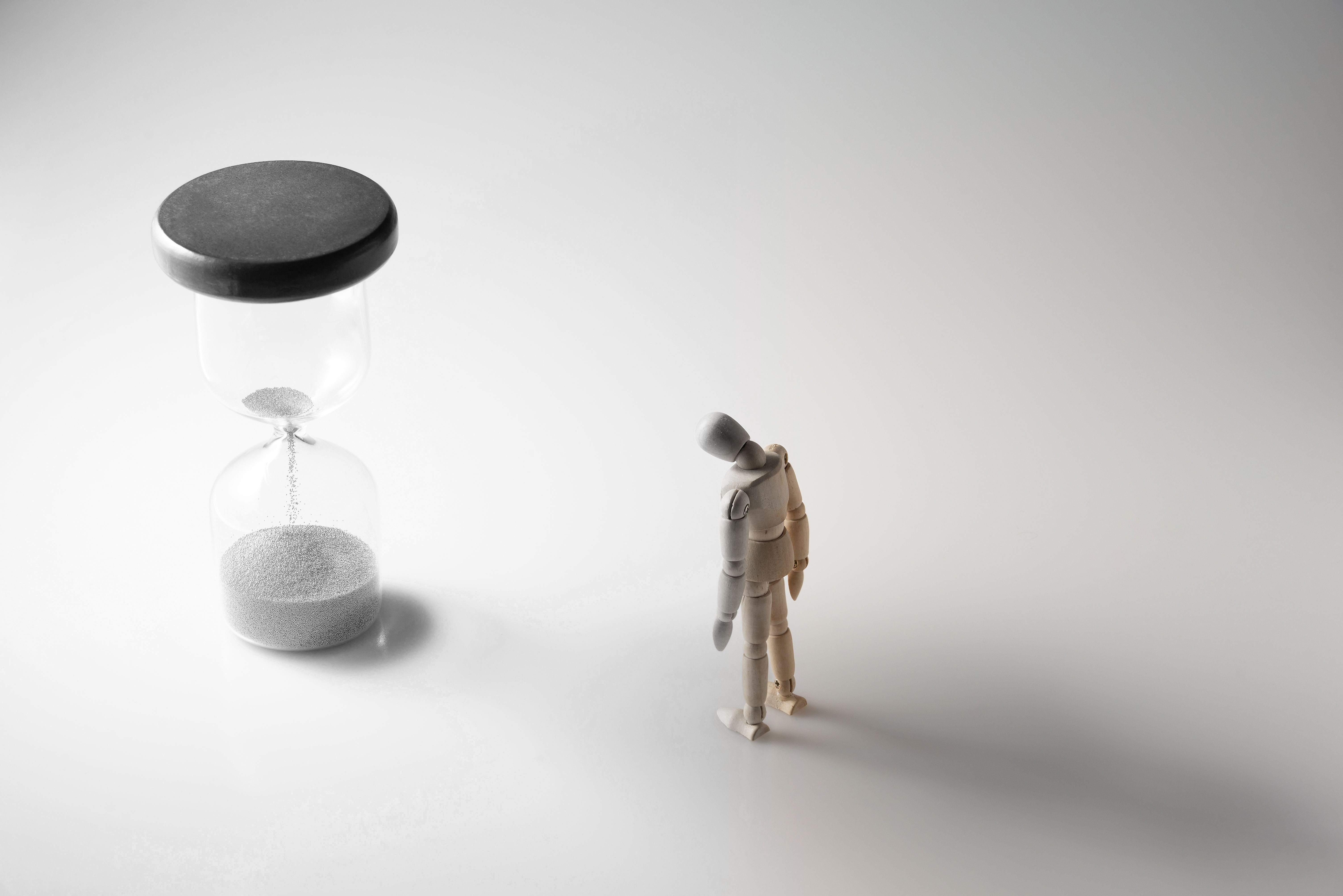 hourglass and wooden figure turing gray while color fading as time running out