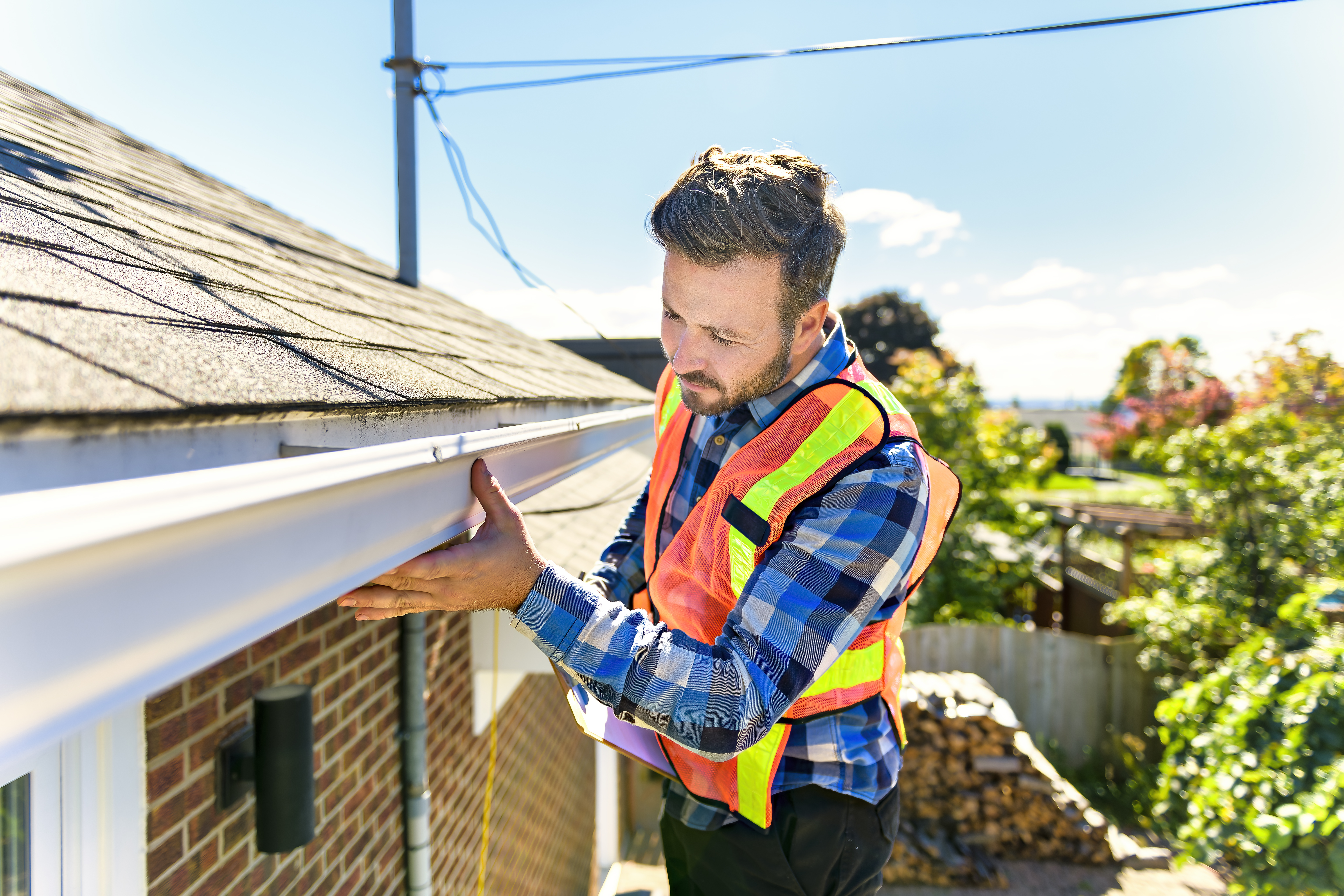 man standing on steps inspecting house roof man standing on steps inspecting house roof