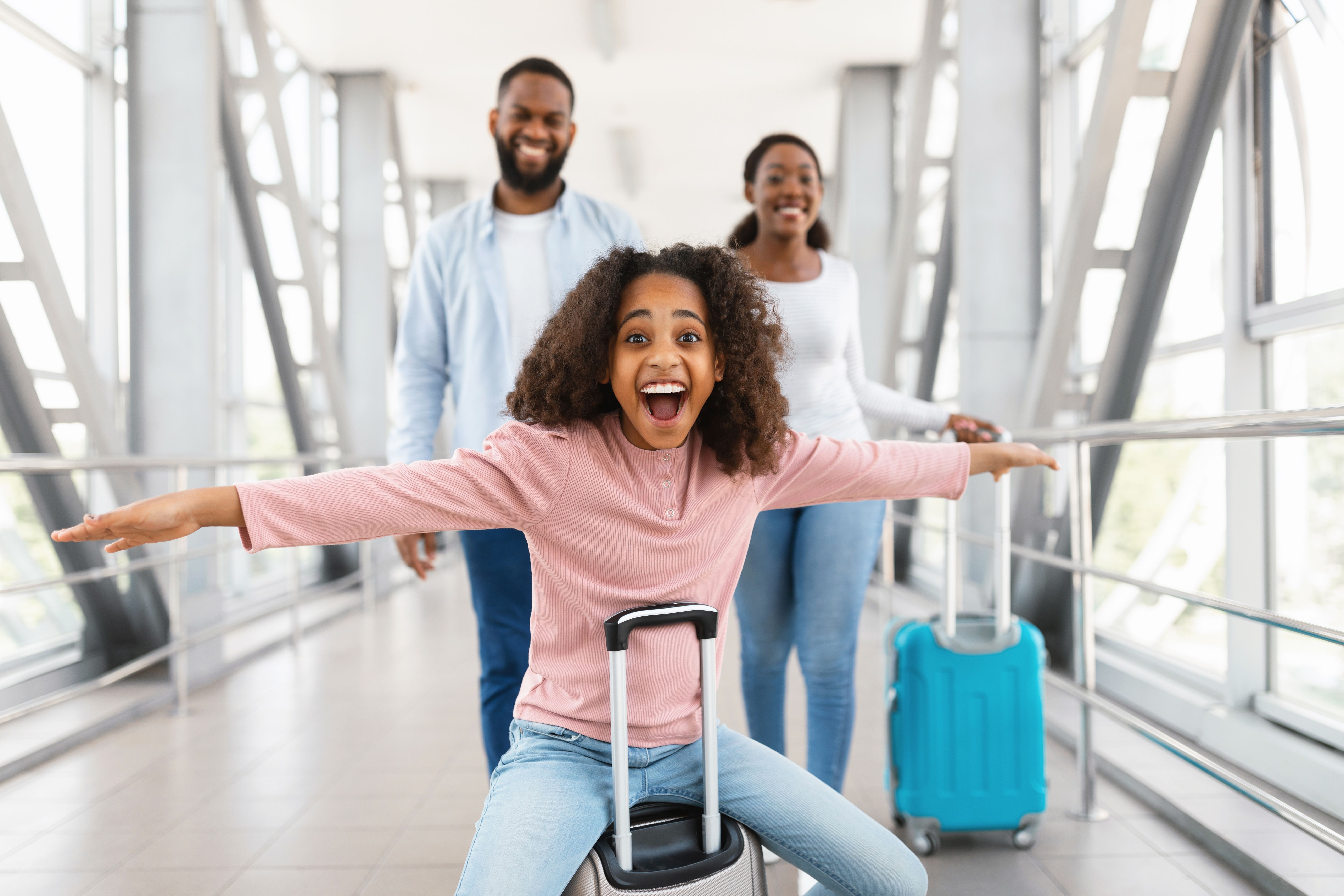 Happy black family traveling with kid, walking in airport