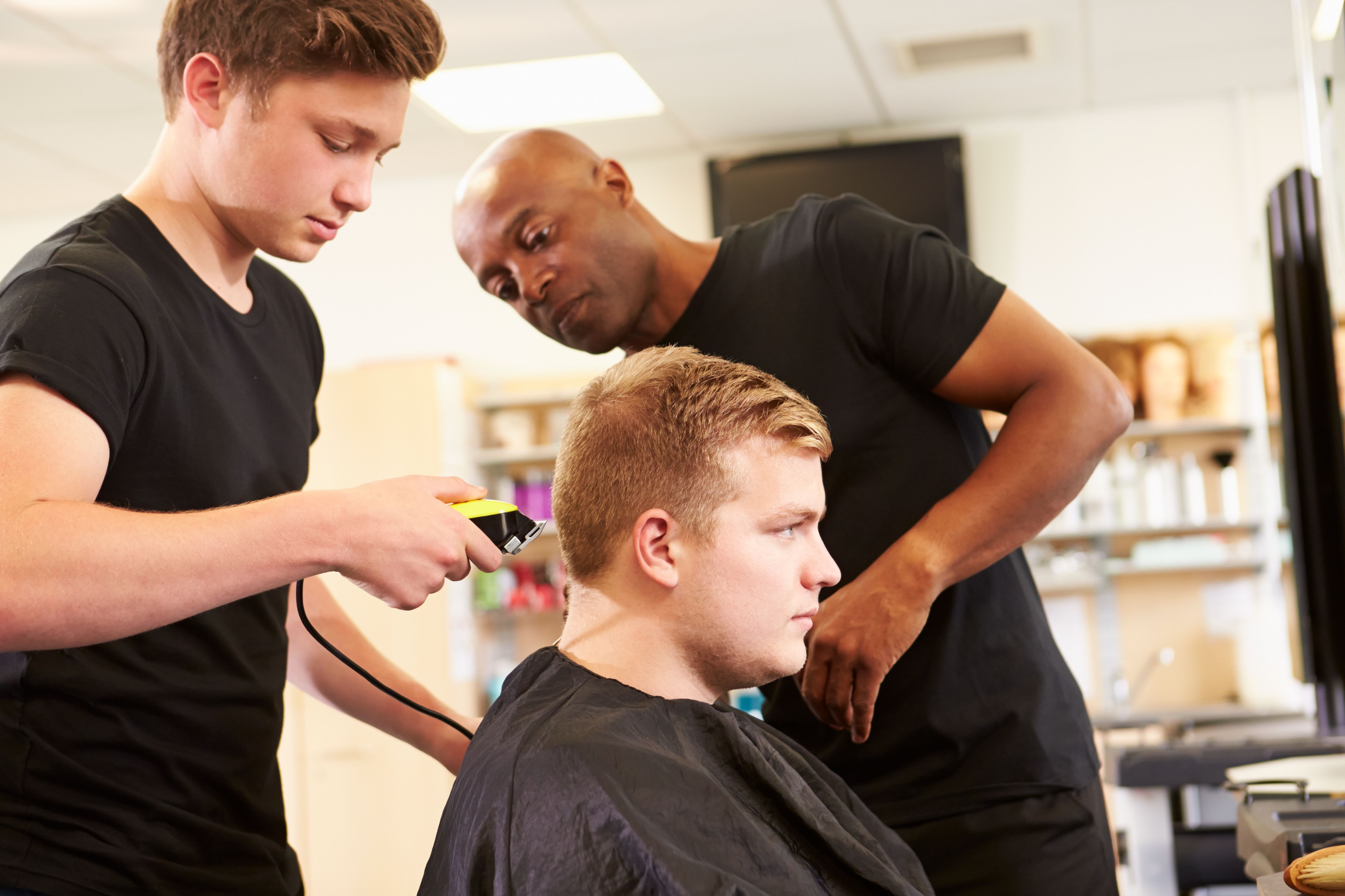 Teacher Helping Students Training To Become Hairdressers
