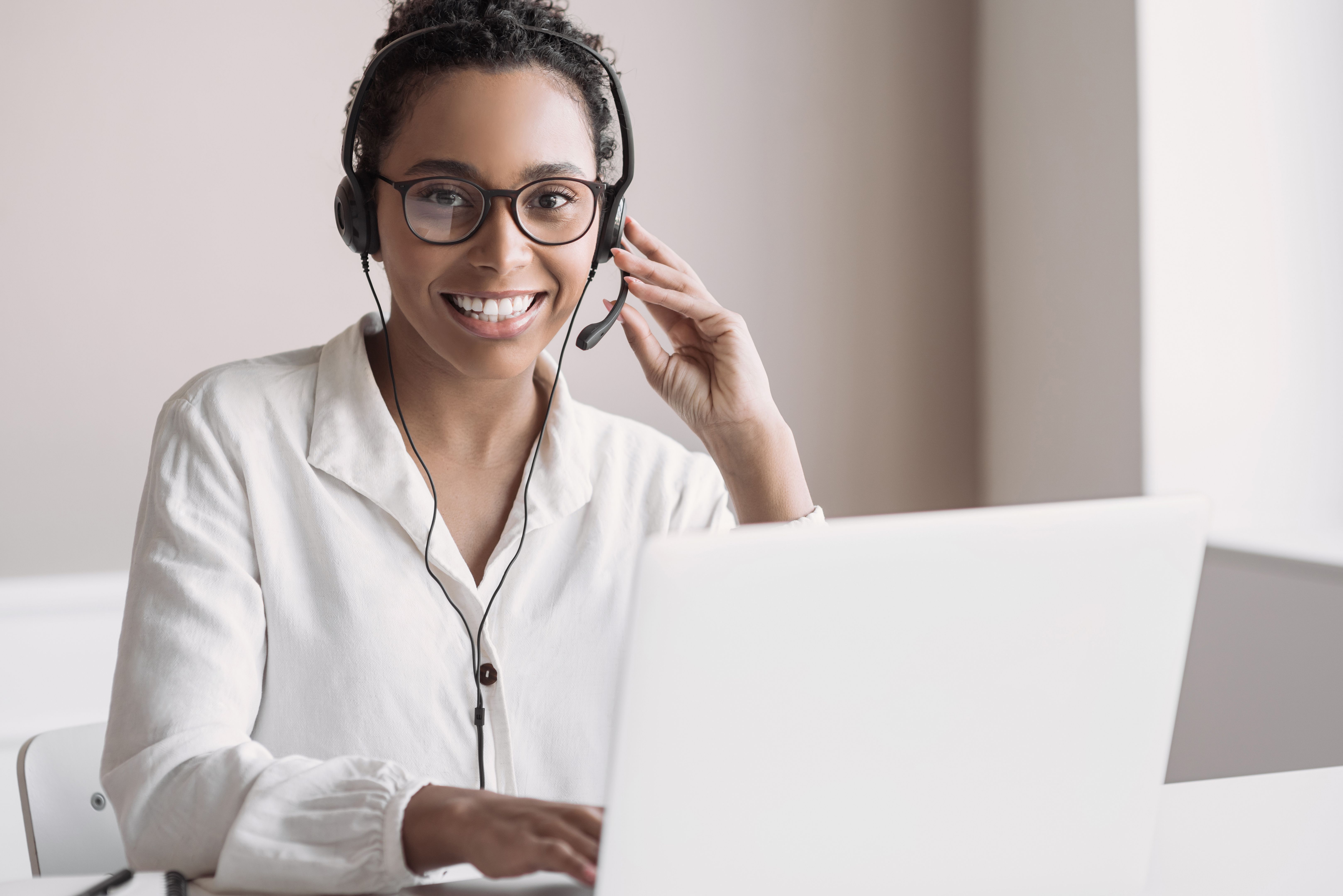 Young woman wearing headset using laptop computer. Customer service assistant talking on phone