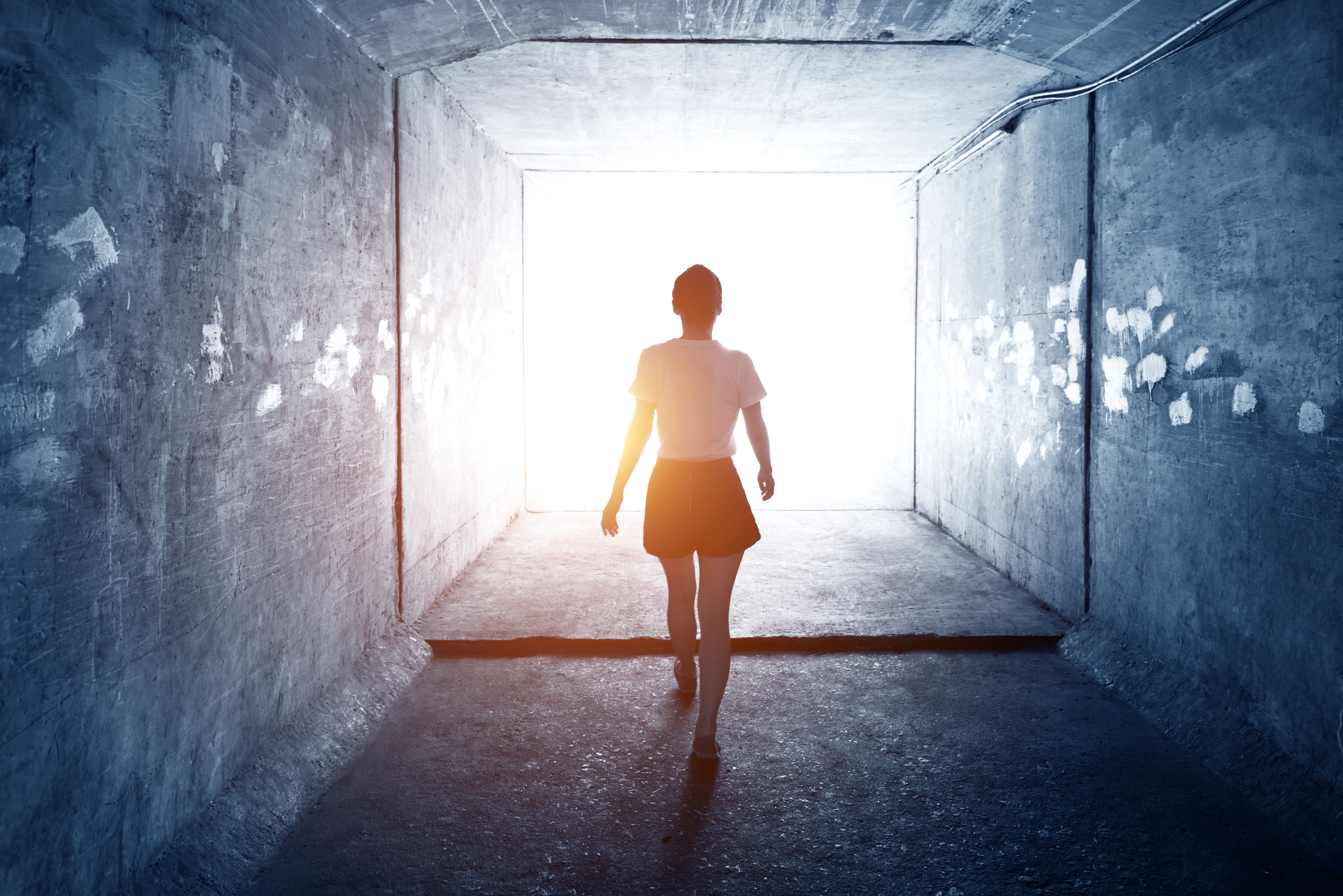 Woman walking through a dark tunnel