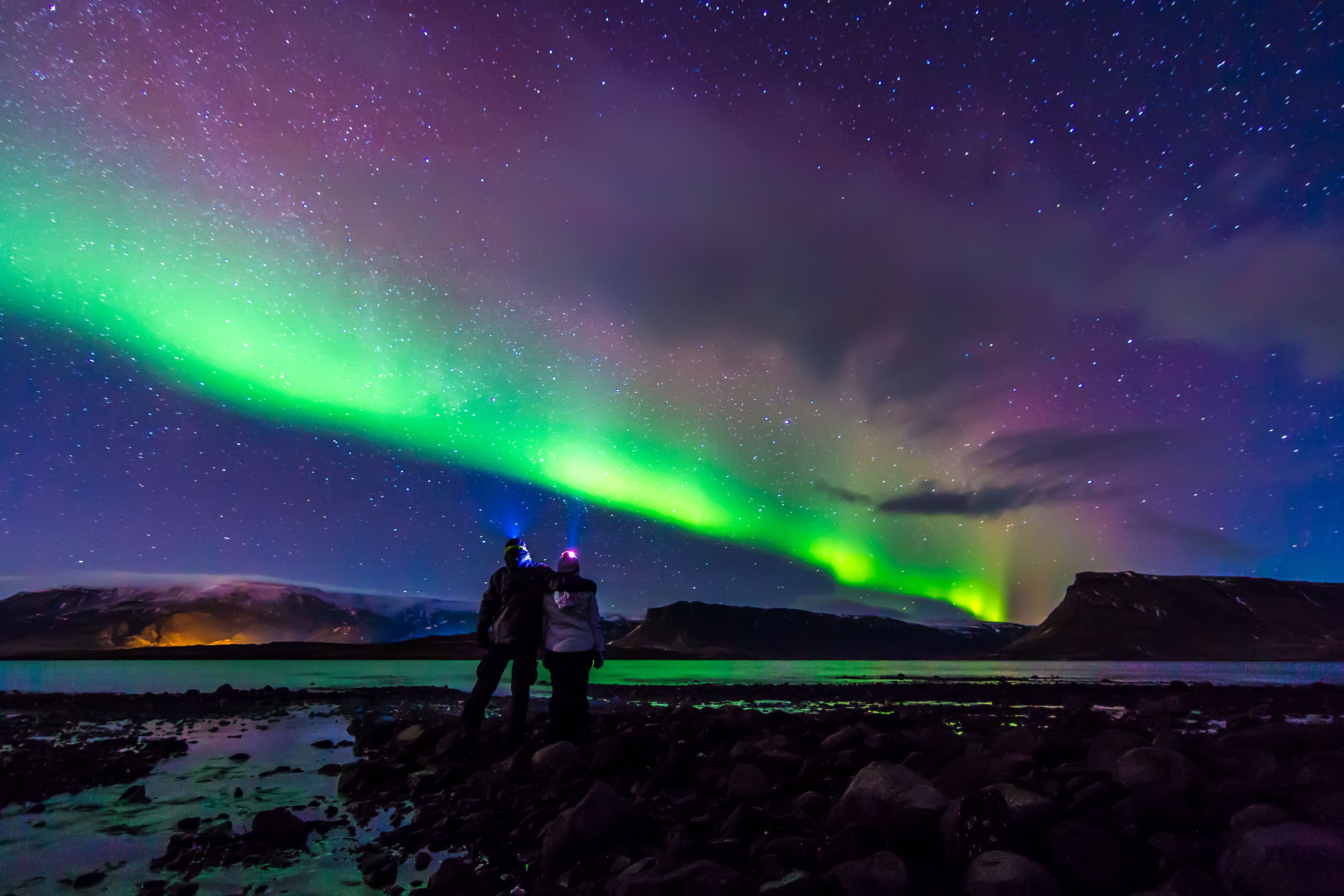 Young Couple hugged under Northern lights Aurora Borealis in Iceland Young Couple hugged under Northern lights Aurora Borealis in Iceland