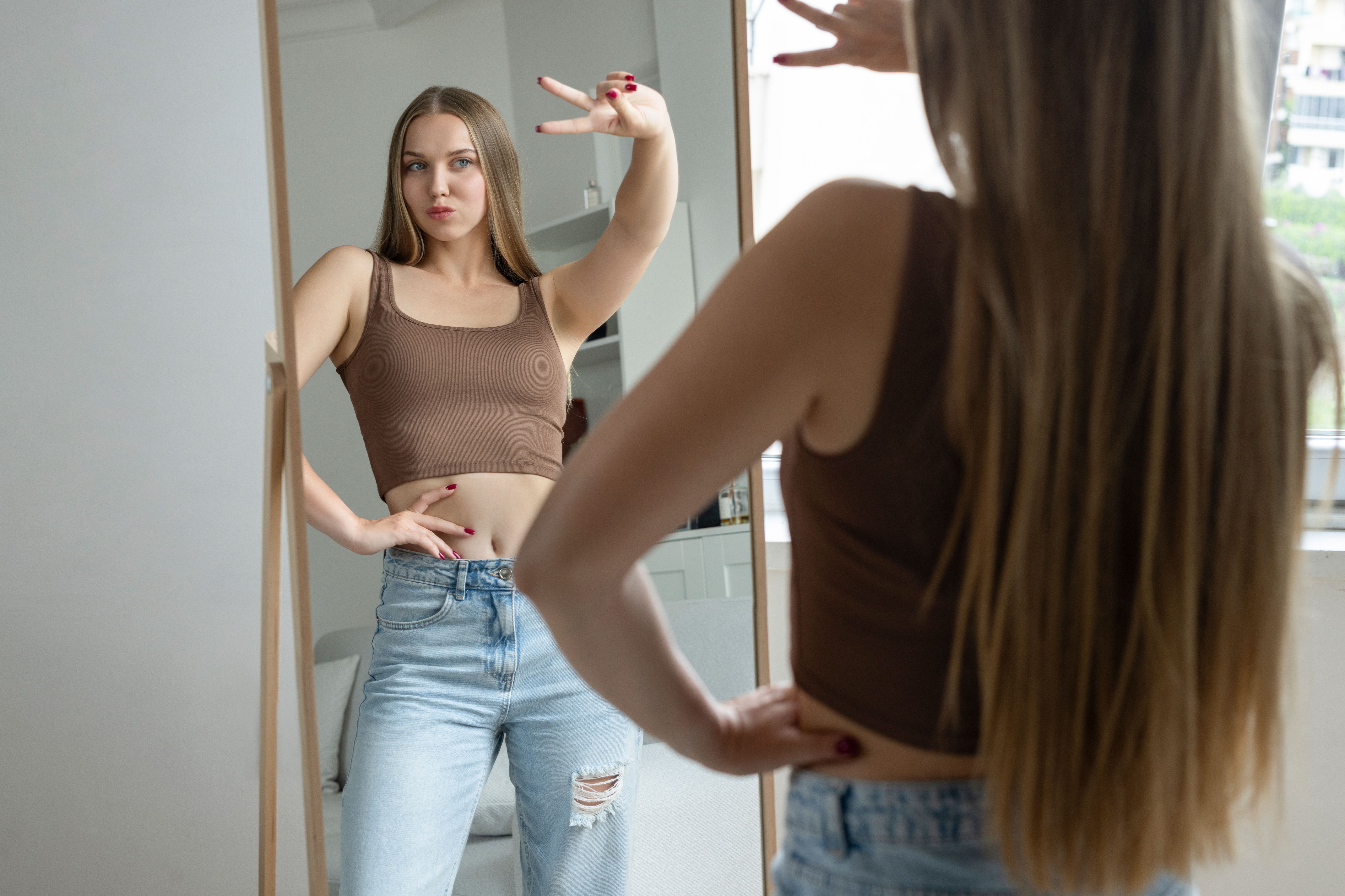 Beautiful woman making a peace sign in front of mirror