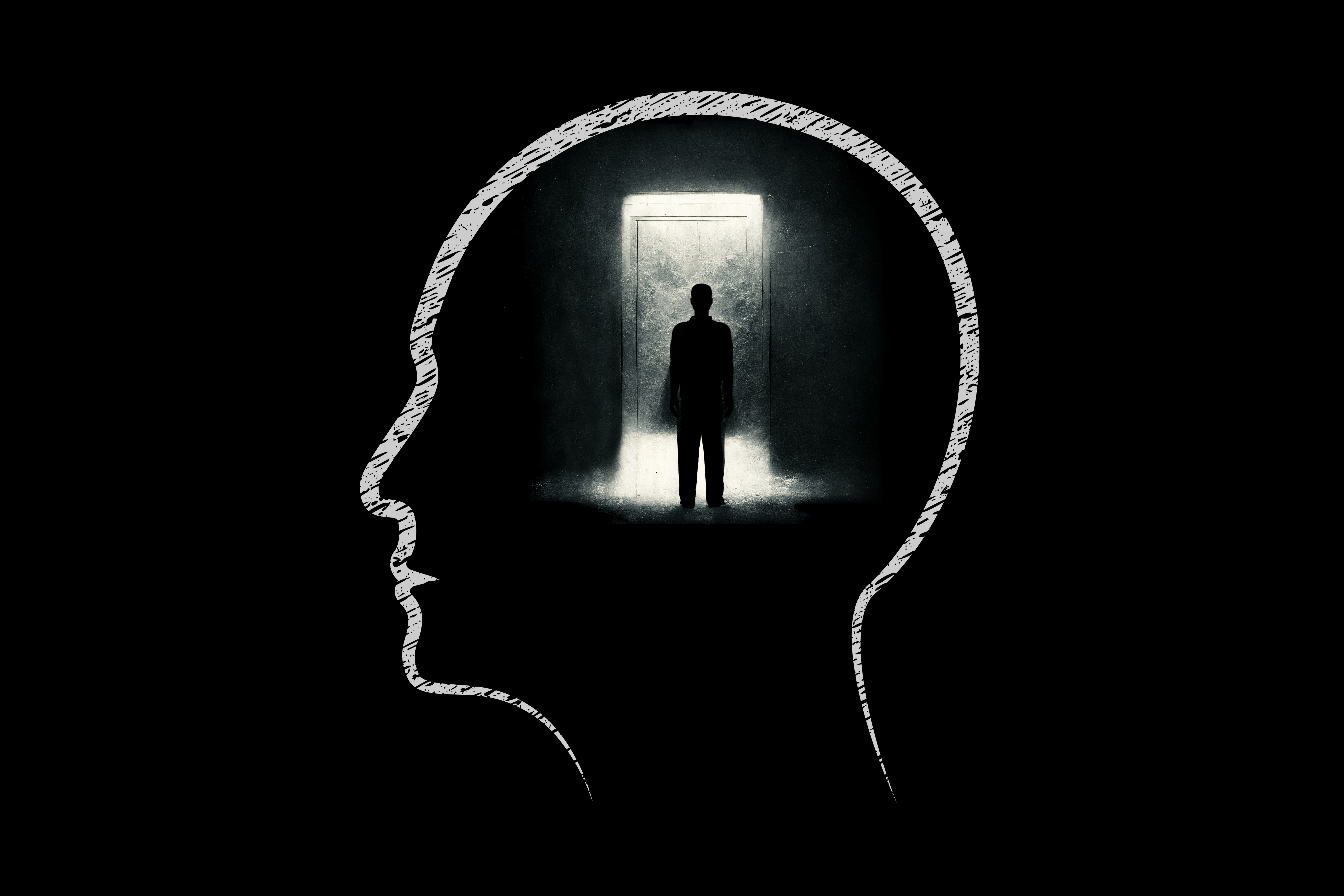 Human head with silhouette of a businessman looking towards a bright doorway in dark room