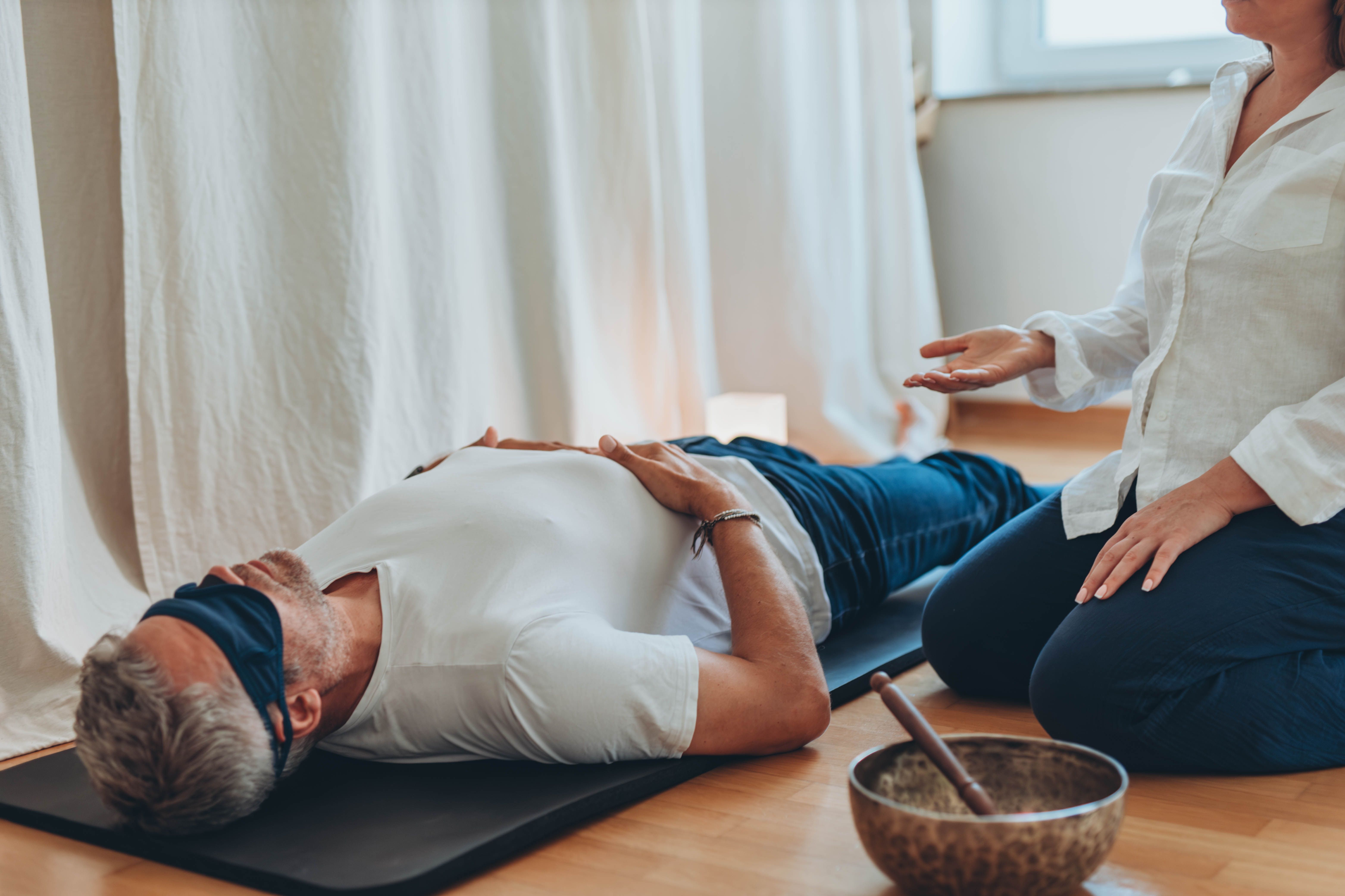 Man and woman practicing mindful breathing together during a meditation session,seated on mats with sound bowls Man and woman practicing mindful breathing together during a meditation session,seated on mats with sound bowls