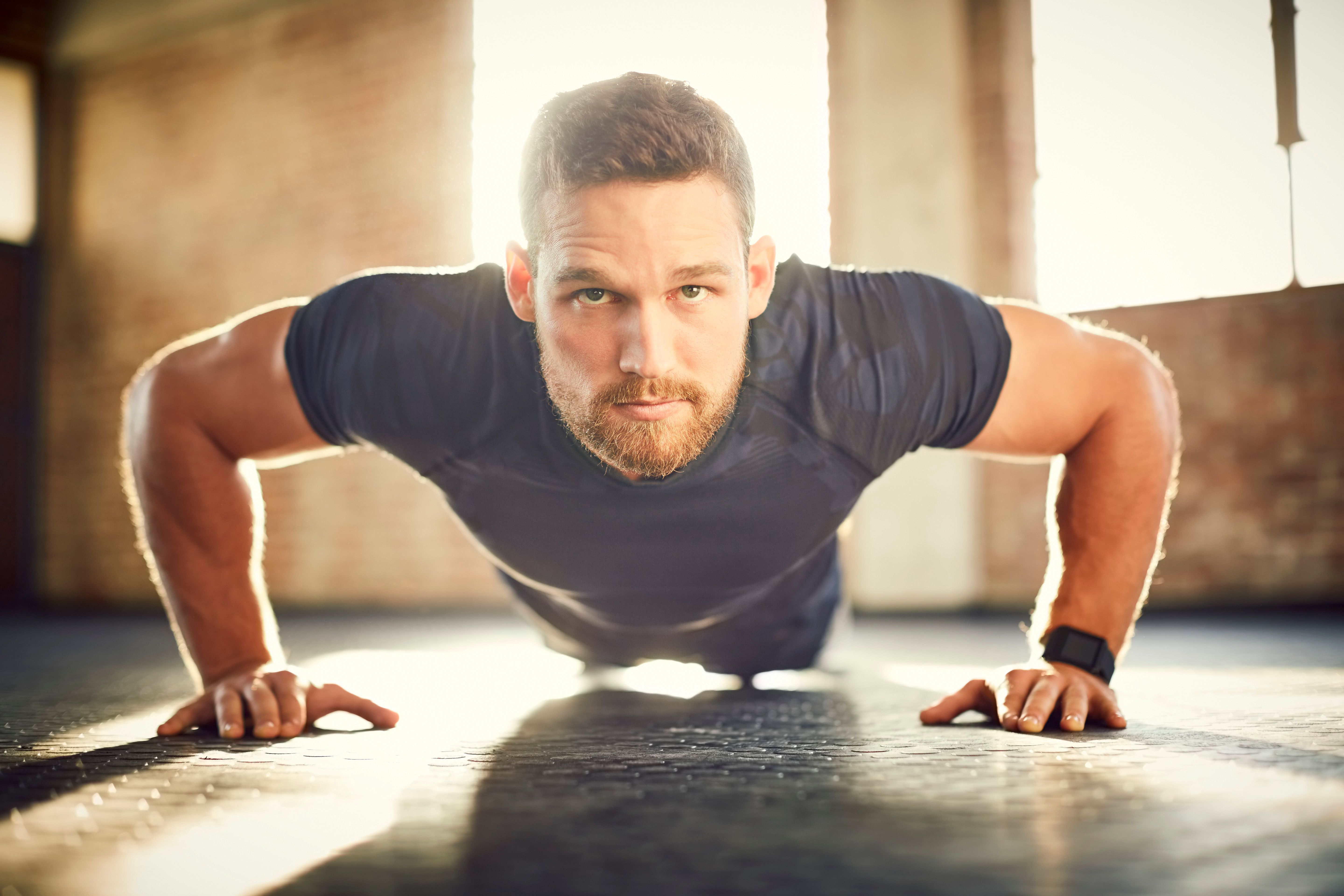 Young male doing push-ups on gym floor