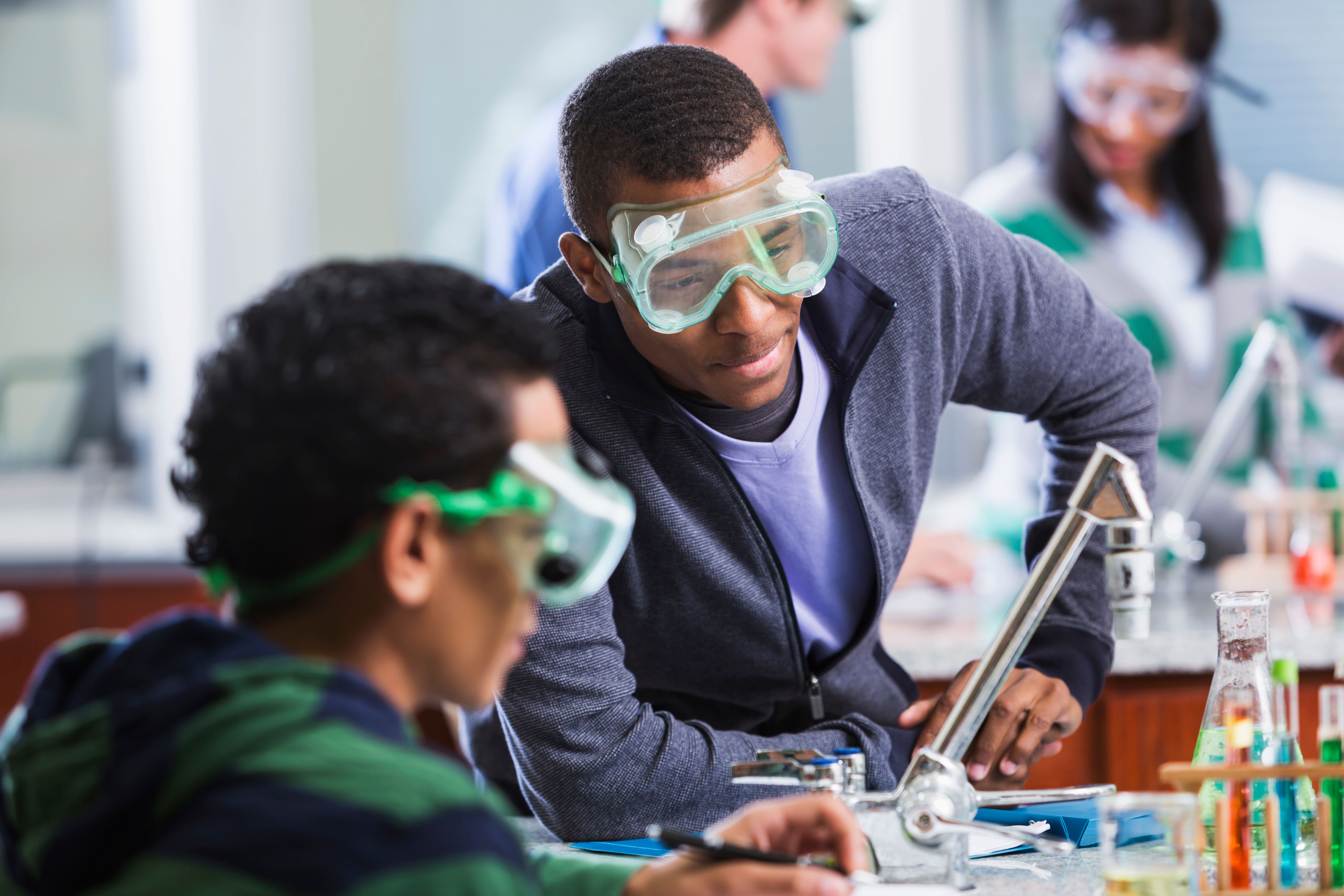 Multi-ethnic students wearing safety glasses in chemistry class Multi-ethnic students wearing safety glasses in chemistry class