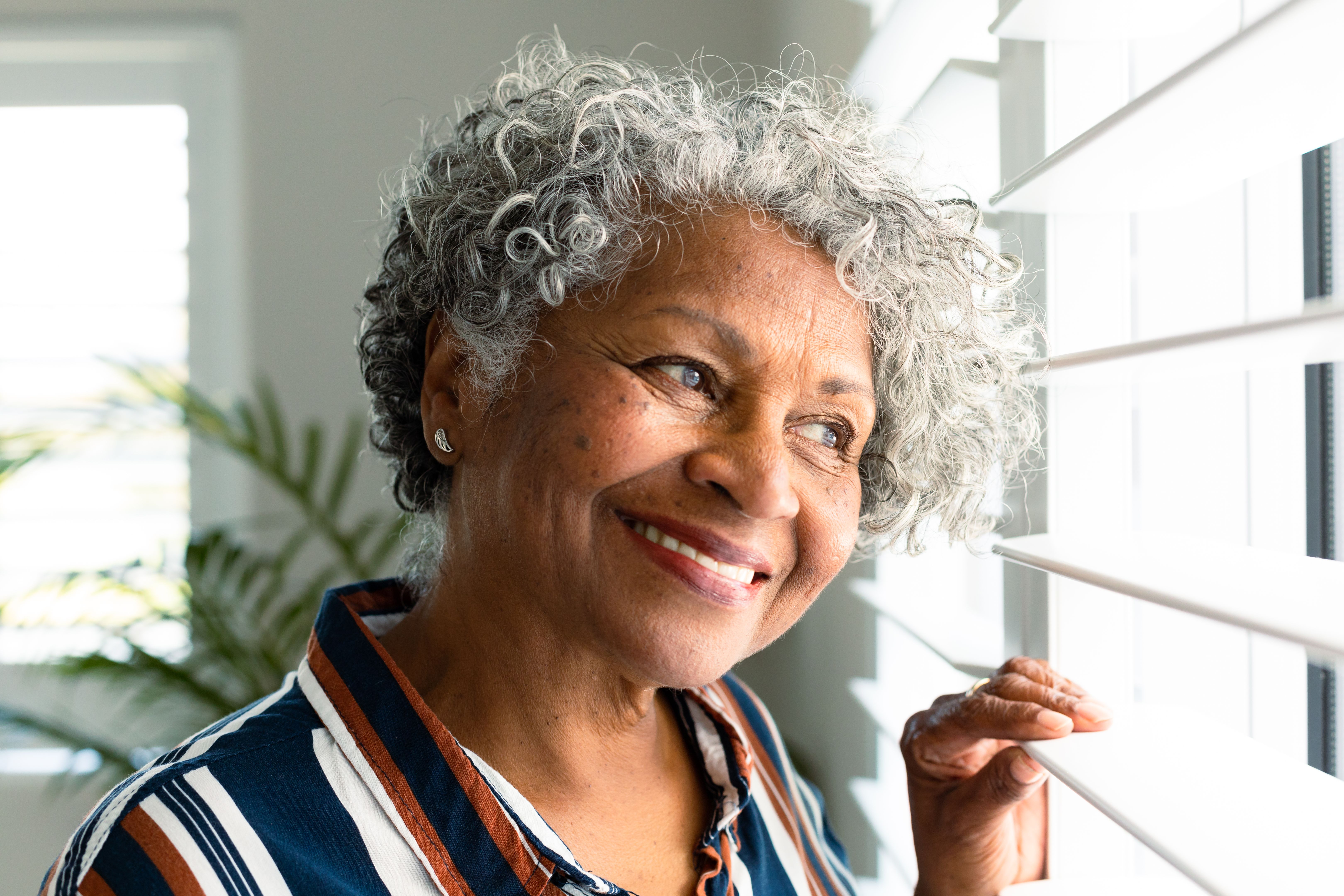 Portrait of smiling african american senior woman looking through window